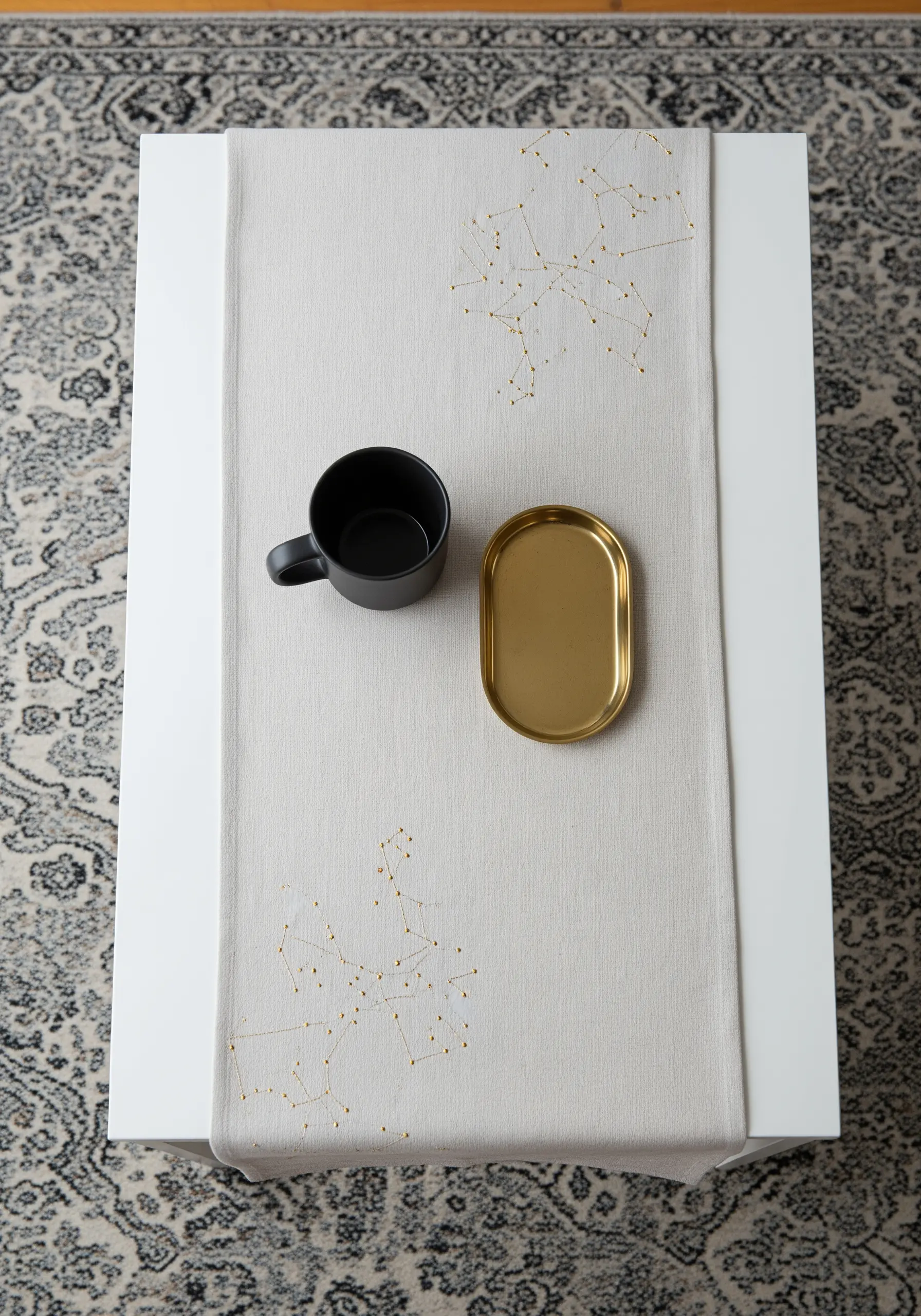 Gold metallic thread embroidered as constellations on a neutral linen table runner.