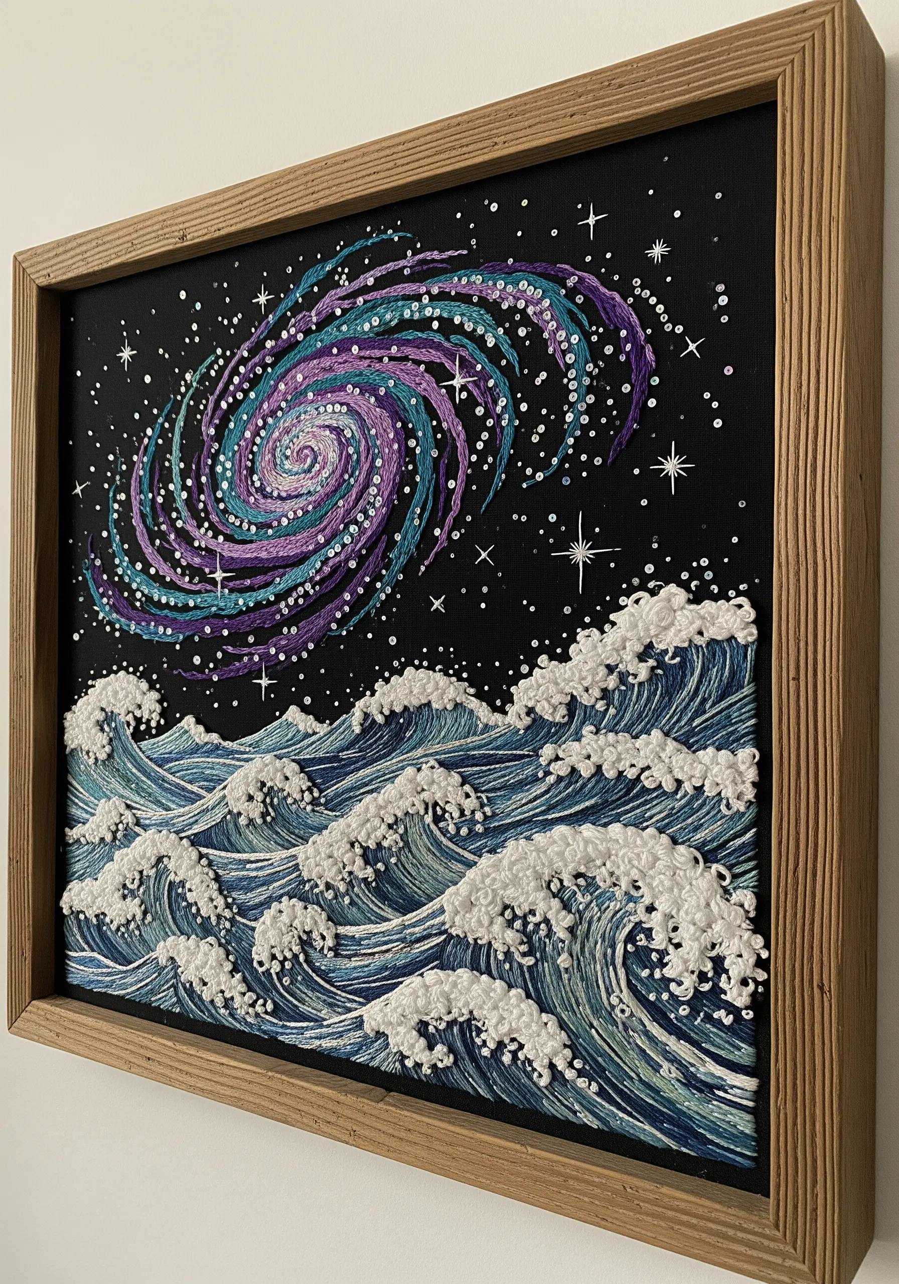 Framed embroidery depicting a swirling purple galaxy over stylized blue and white ocean waves.