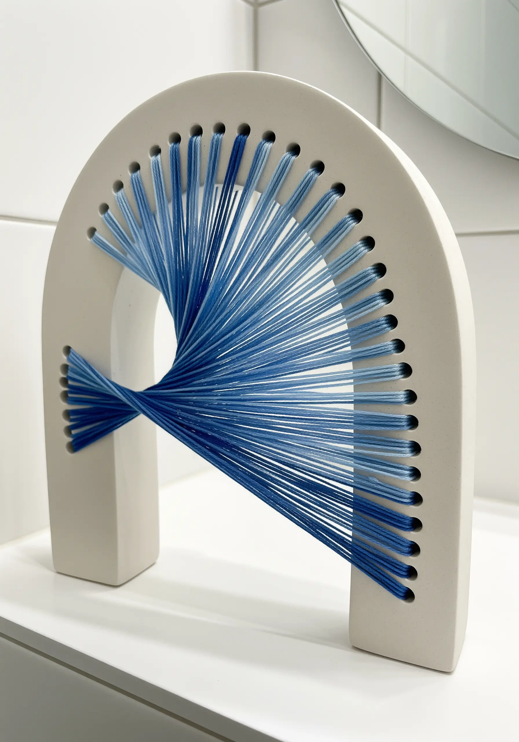 White ceramic arch strung with blue thread