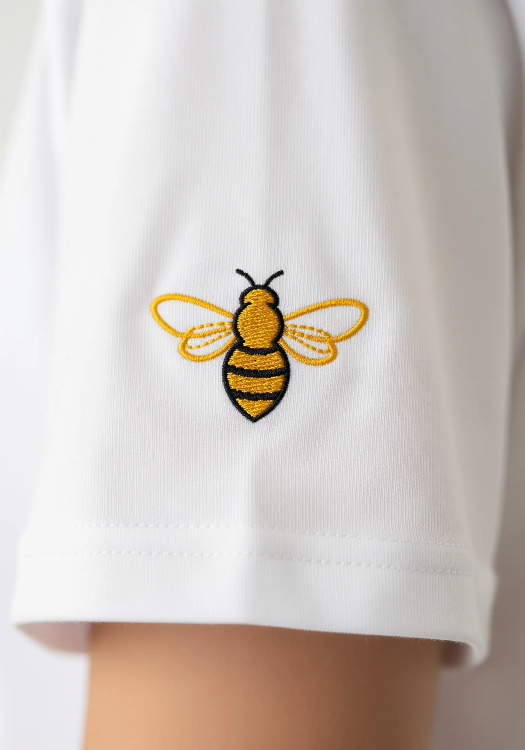 A clean, graphic bee embroidered in yellow and black on a t-shirt sleeve.