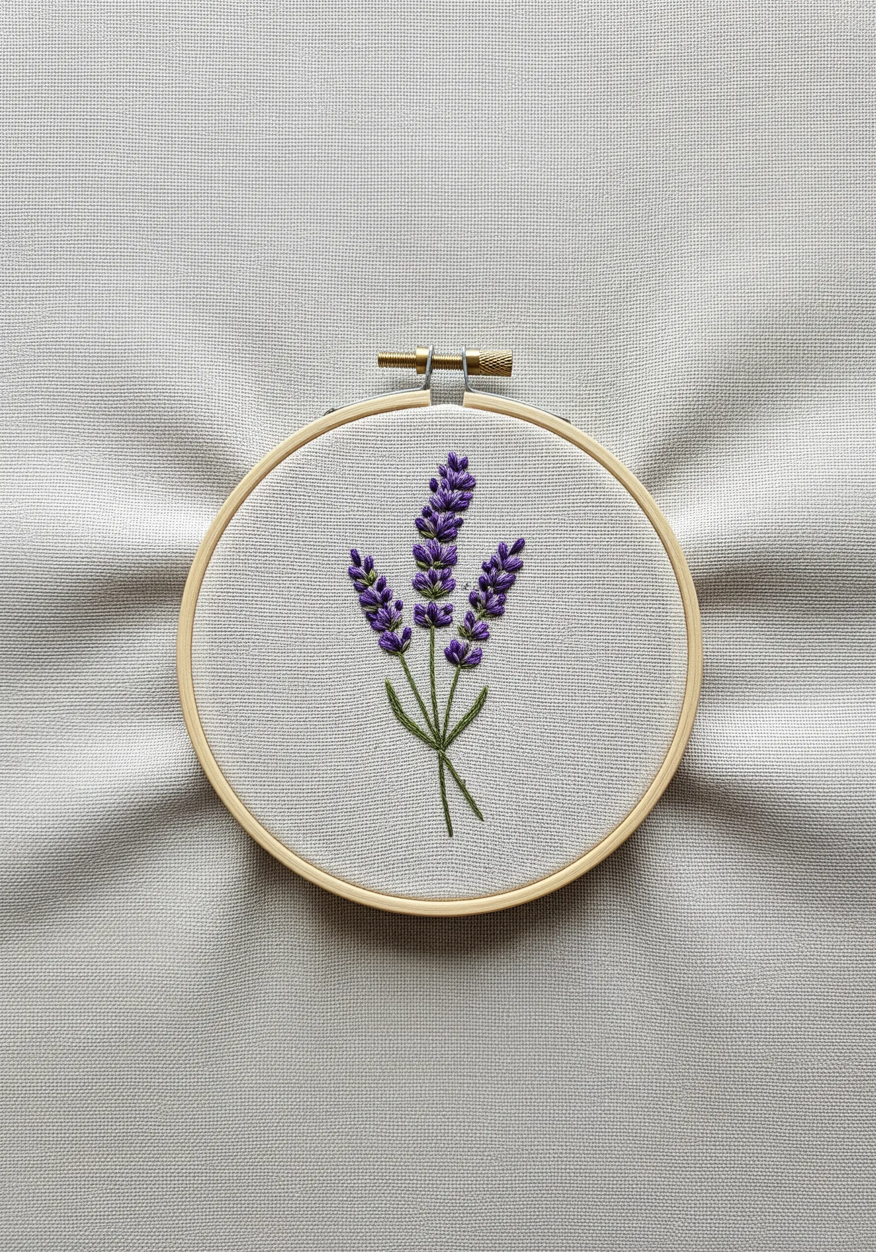A sprig of lavender stitched with purple French knots and green stem stitch in a hoop.