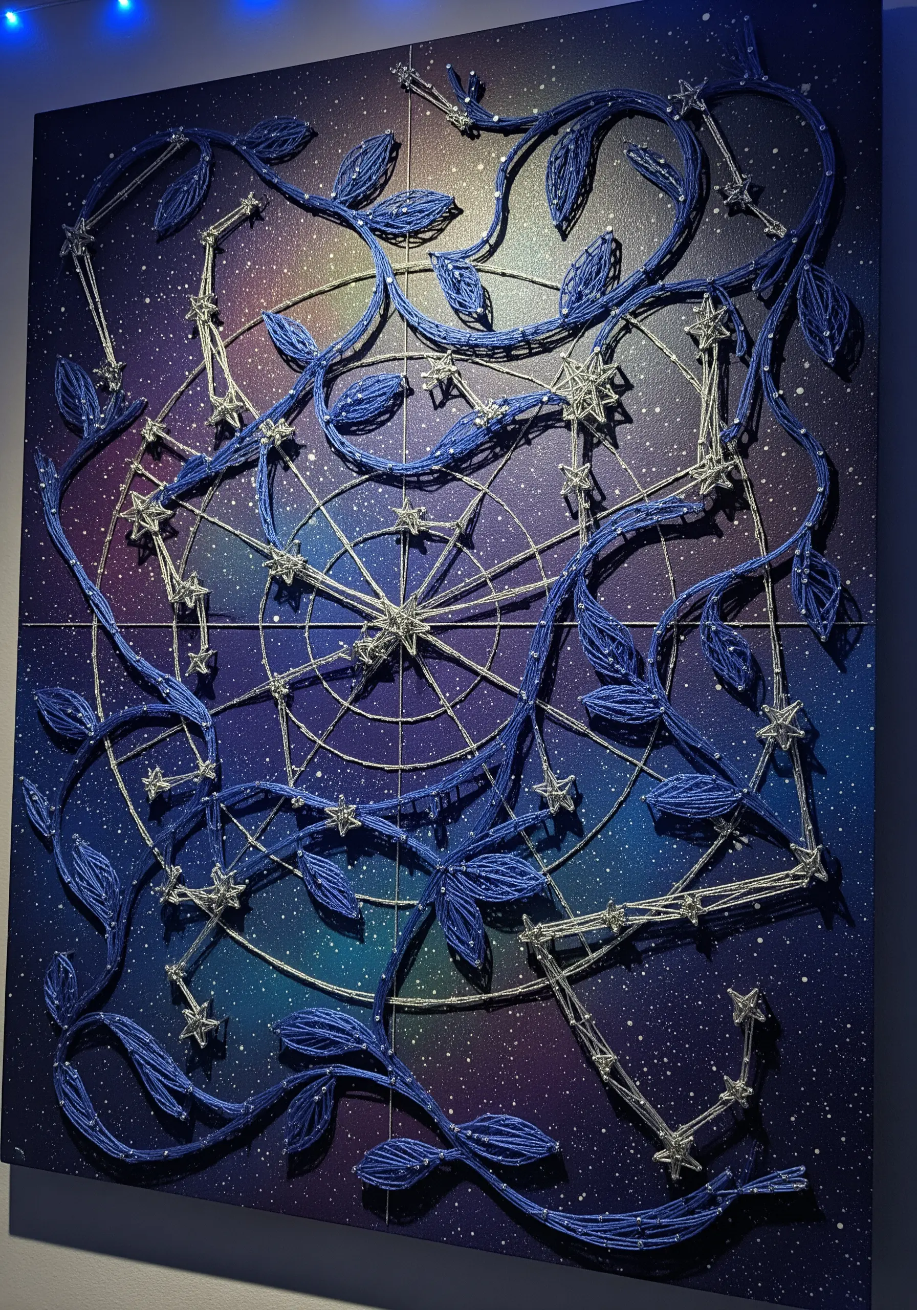 Celestial string art with blue vines and silver star constellations over a painted galaxy background.