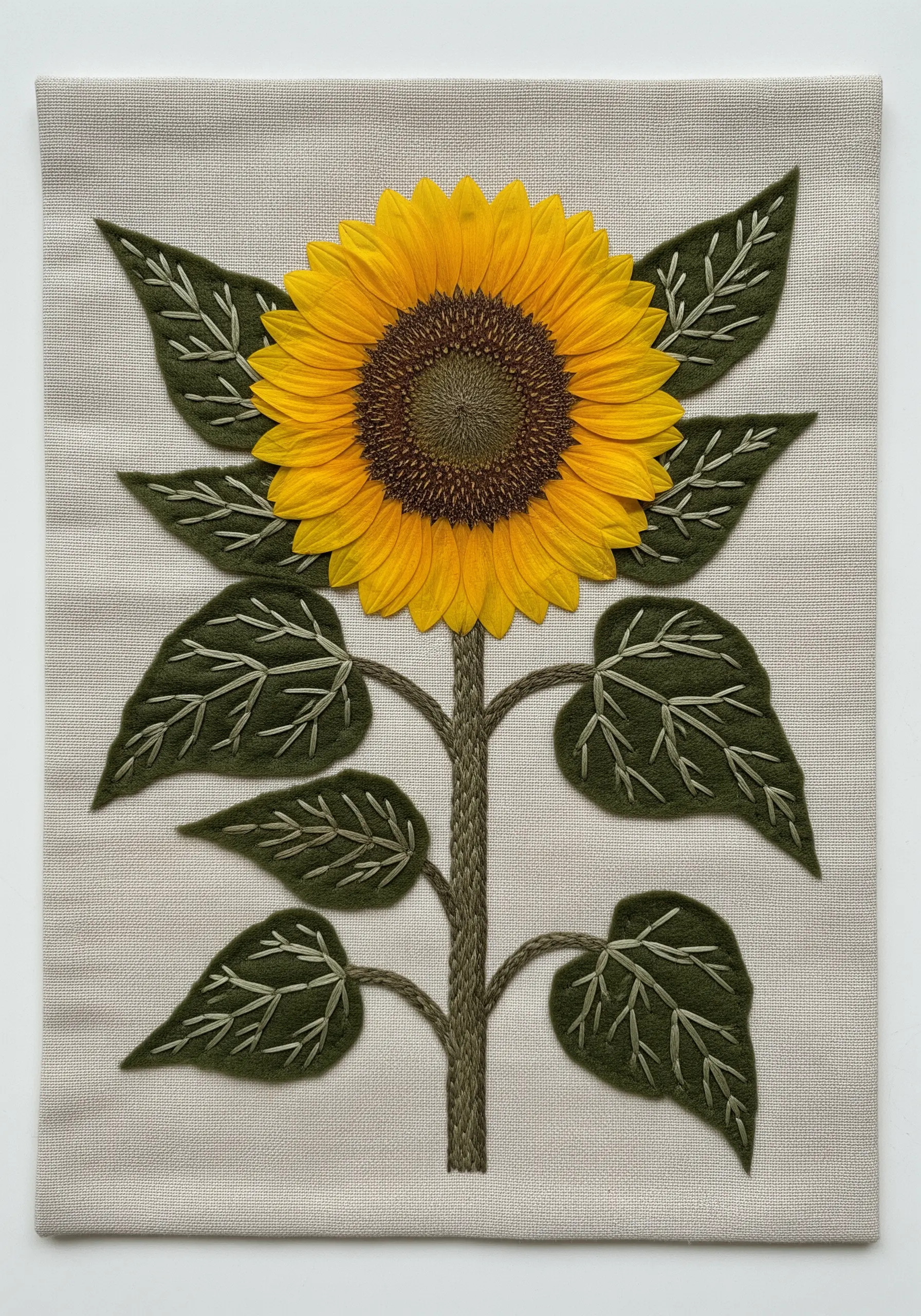 Mixed-media art of a sunflower with a real pressed flower head and embroidered felt leaves.