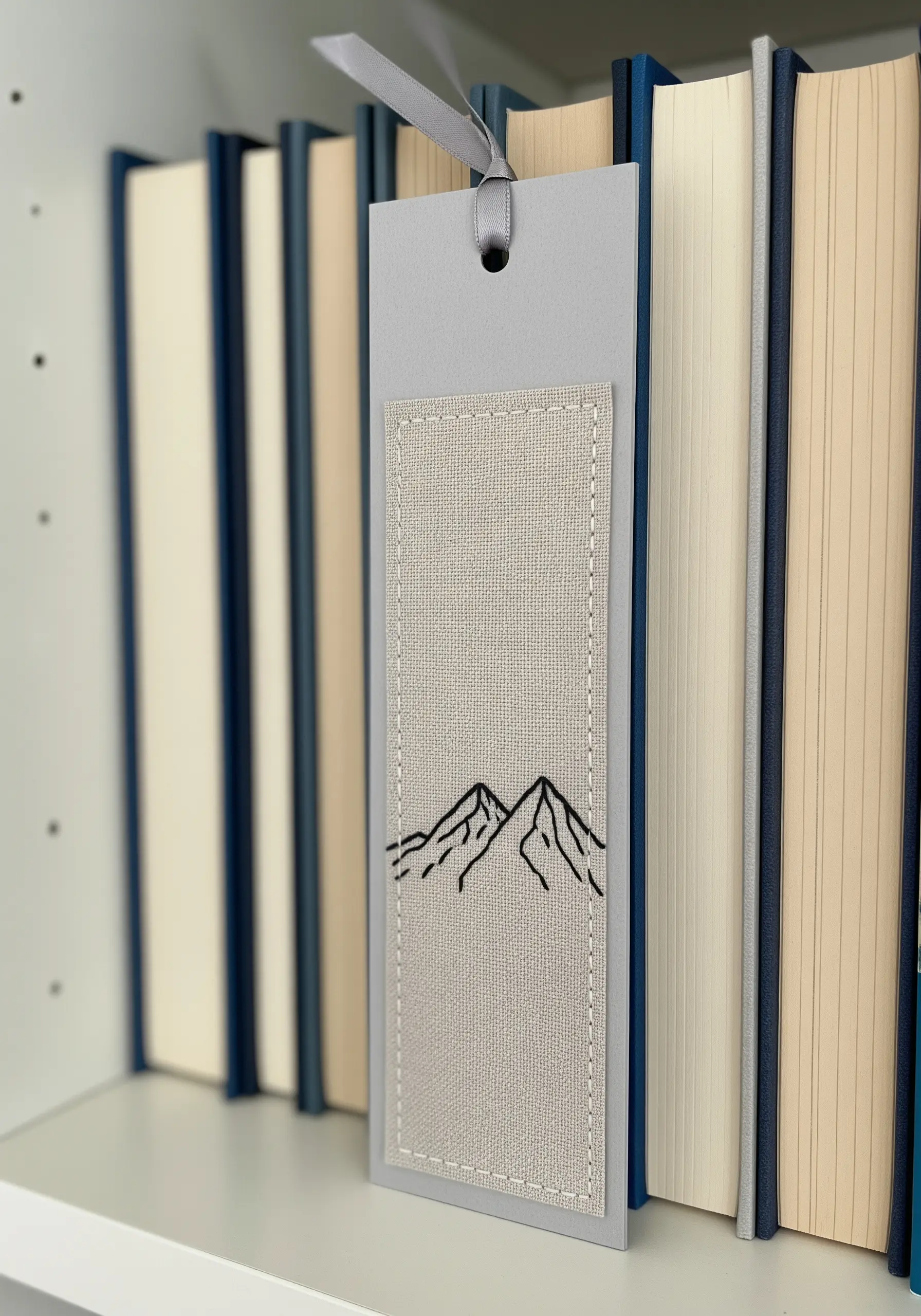 A bookmark made from cardstock with an embroidered fabric panel showing a mountain outline.