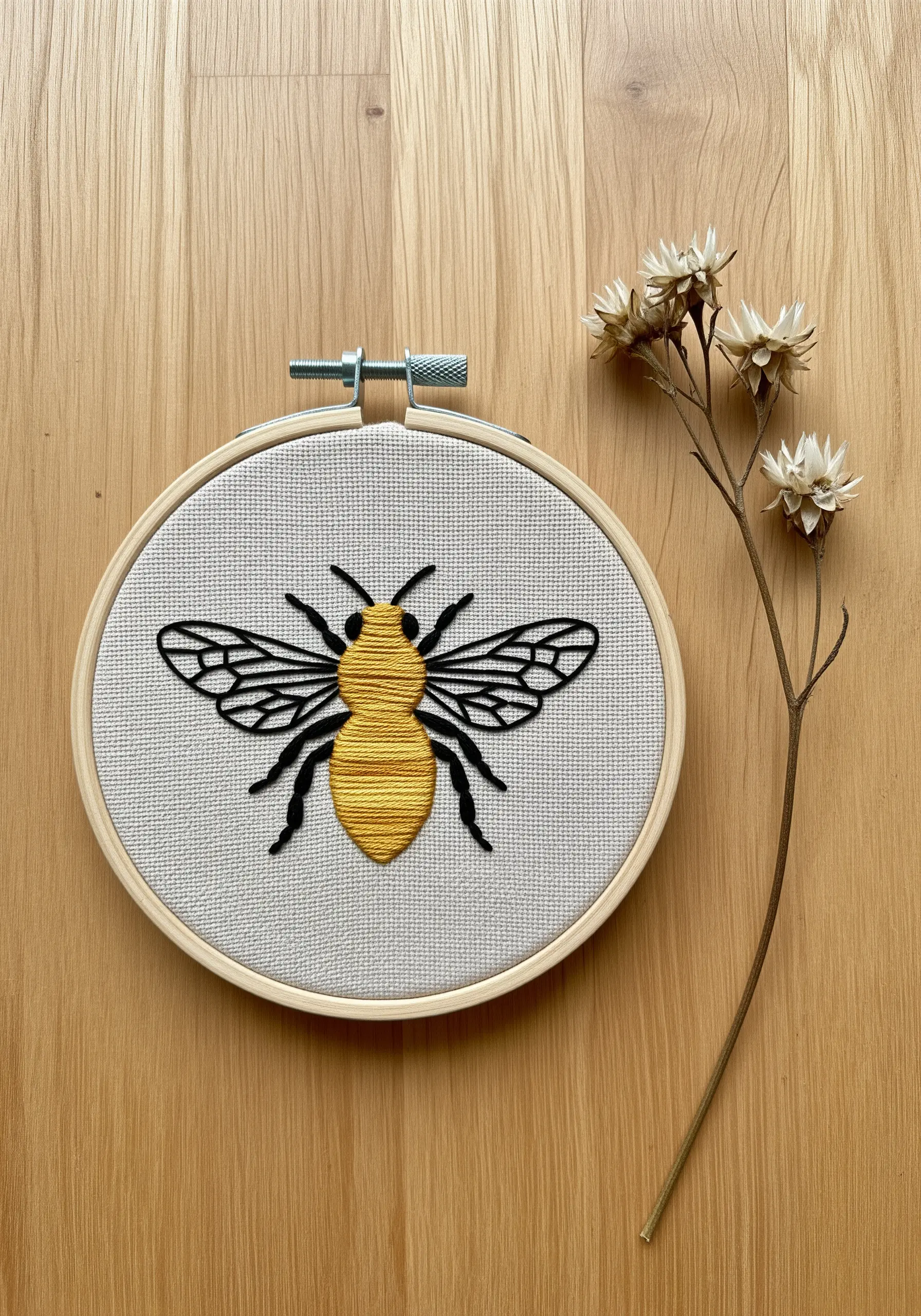 A honeybee with a yellow satin-stitched body and delicate black line-work for wings and legs.