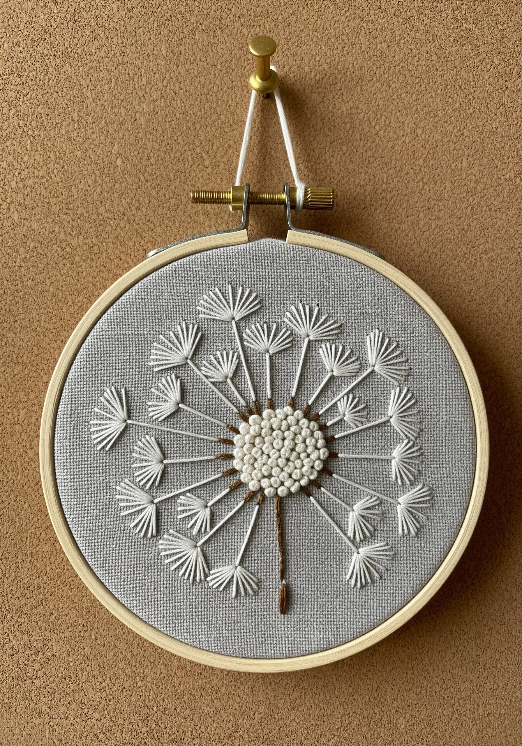 Detailed dandelion embroidery with French knots and detached chain stitches.