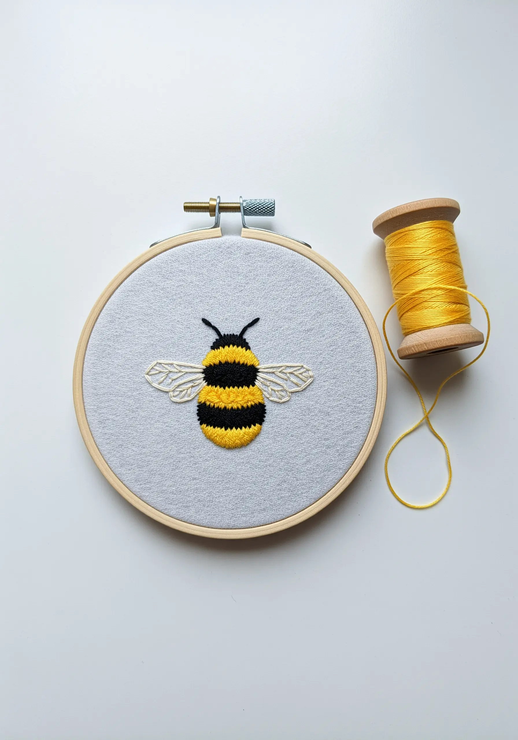 A fluffy embroidered bumblebee with satin stitch stripes and delicate wings.