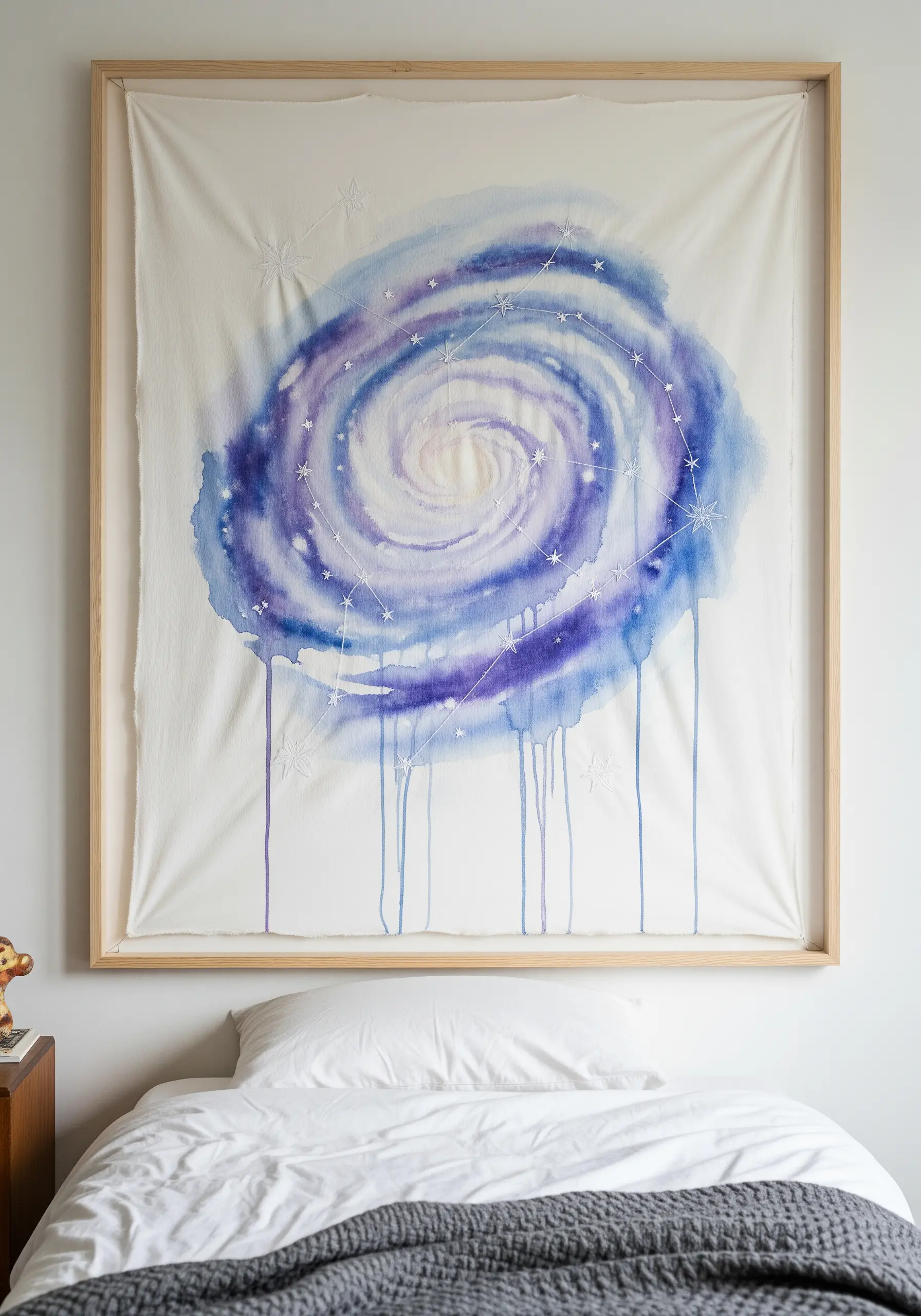 A large framed textile with a watercolor galaxy and embroidered constellations.
