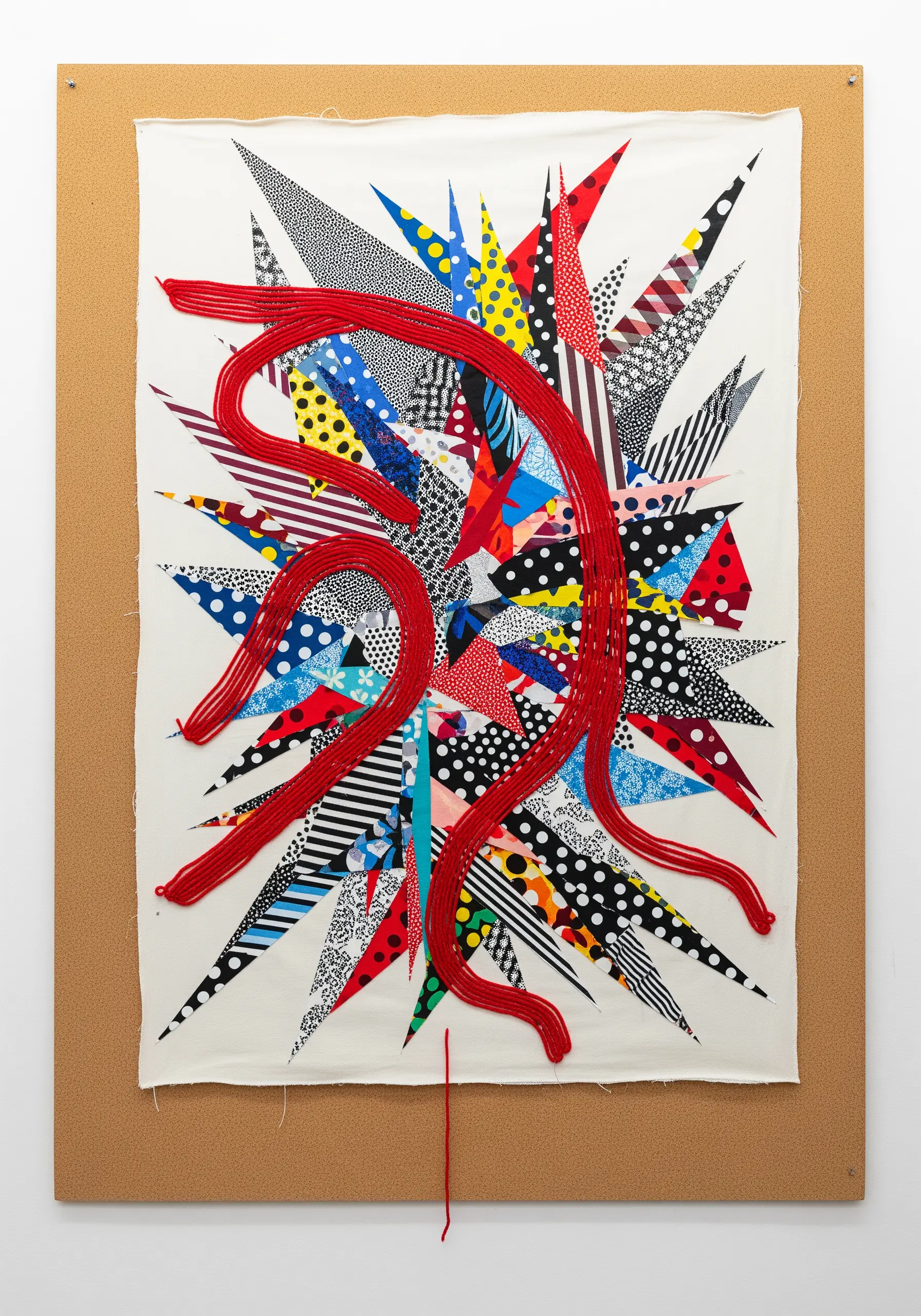 A vibrant abstract collage of patterned fabric scraps with a thick red yarn element snaking through.