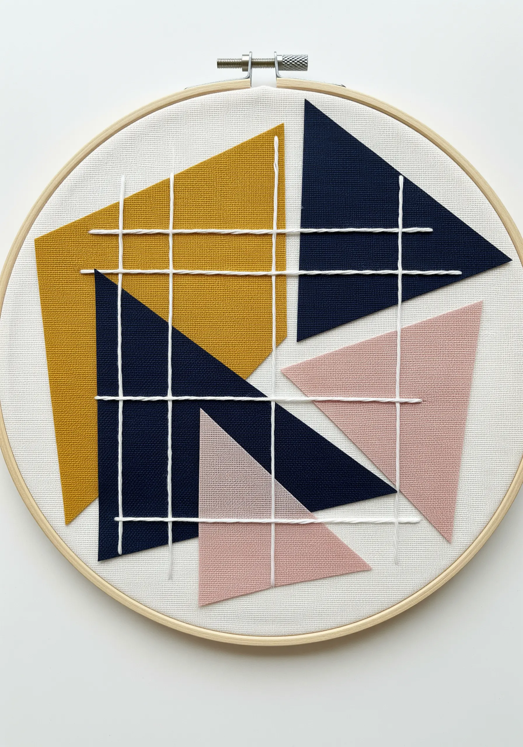 Abstract geometric embroidery with navy, yellow, and pink triangles and a white thread grid.
