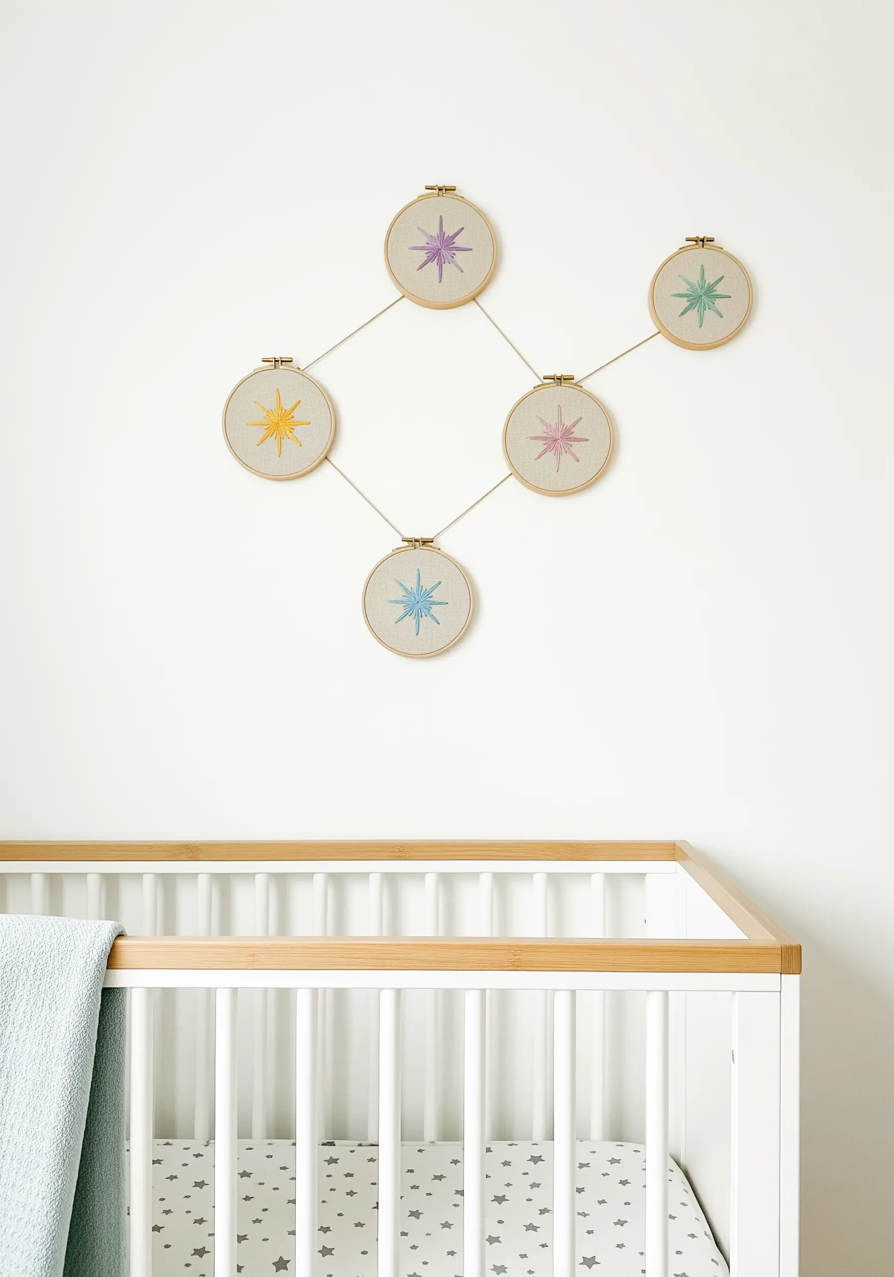 Five embroidery hoops with starbursts connected by threads on a nursery wall.