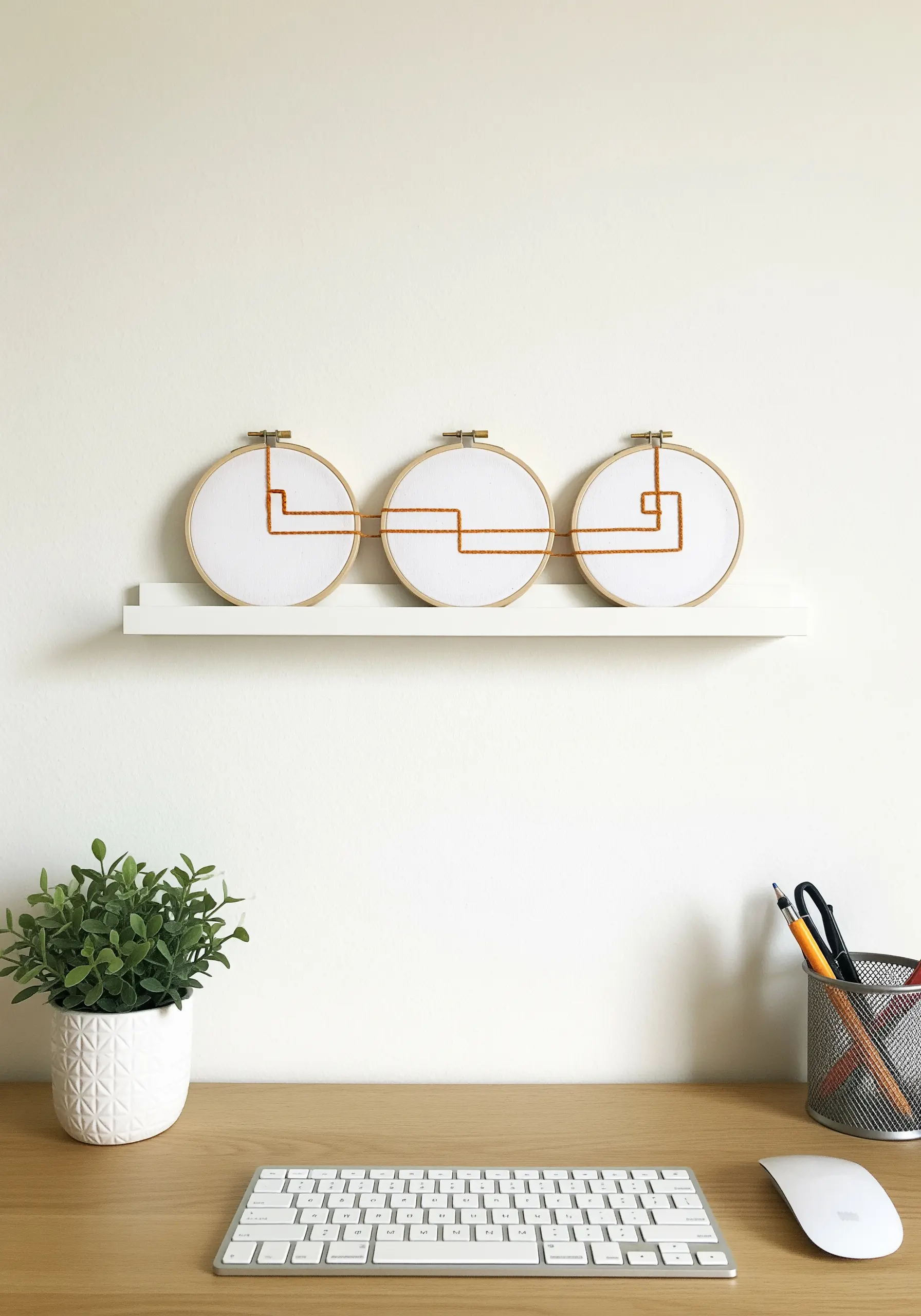 Three embroidery hoops with a continuous orange line forming a circuit pattern.