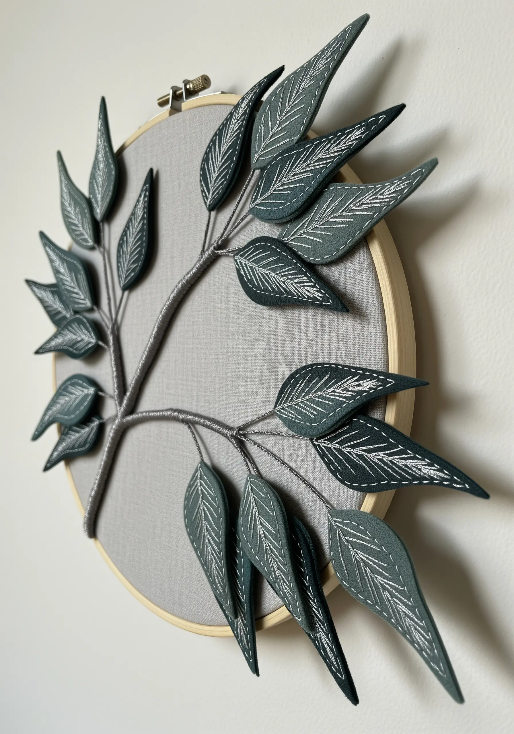 A hoop art piece with 3D fabric leaves that are wired and stitched, creating a sculptural effect.