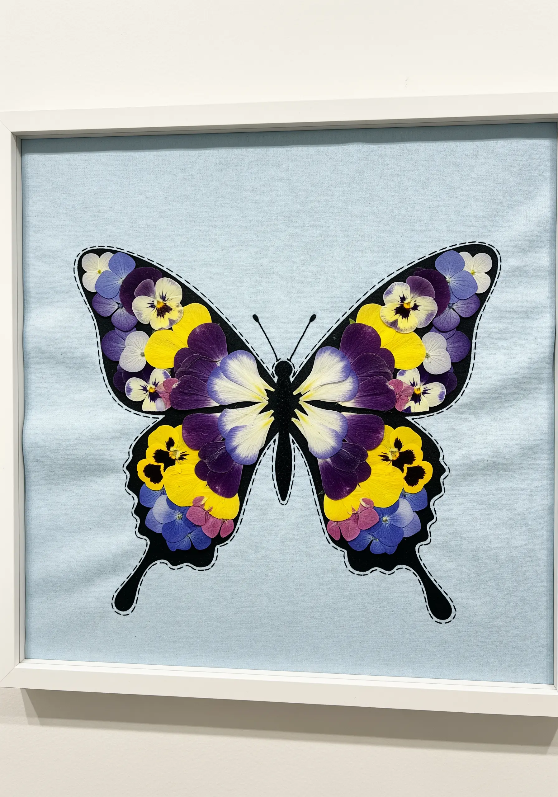A butterfly shape outlined in black stitch and filled in with a mosaic of colorful flower petals.