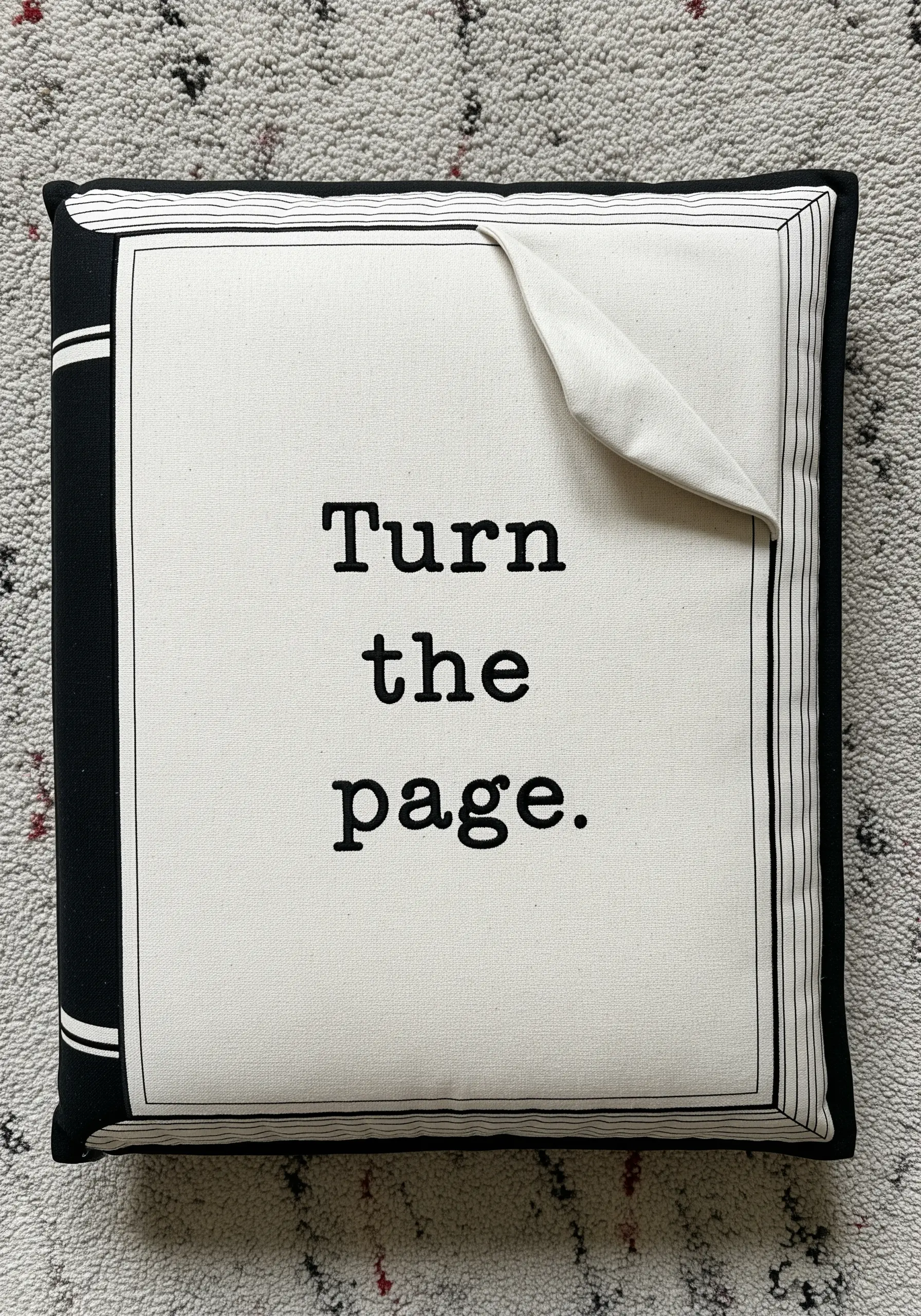 A pillow designed to look like a book, with an appliqué page turning at the corner.