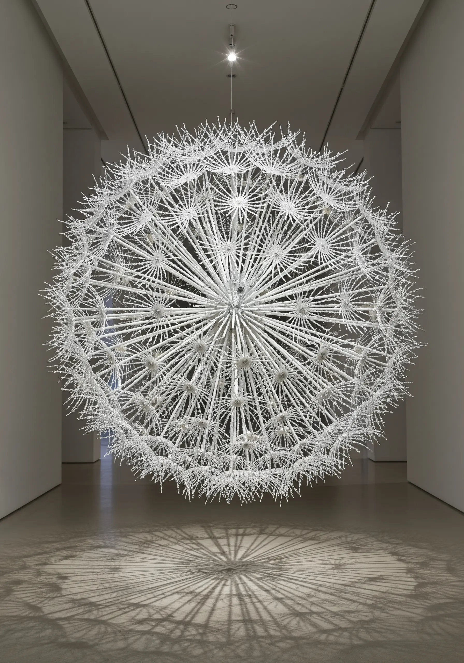 A massive, spherical sculpture resembling a dandelion head, made from thousands of white plastic rods.