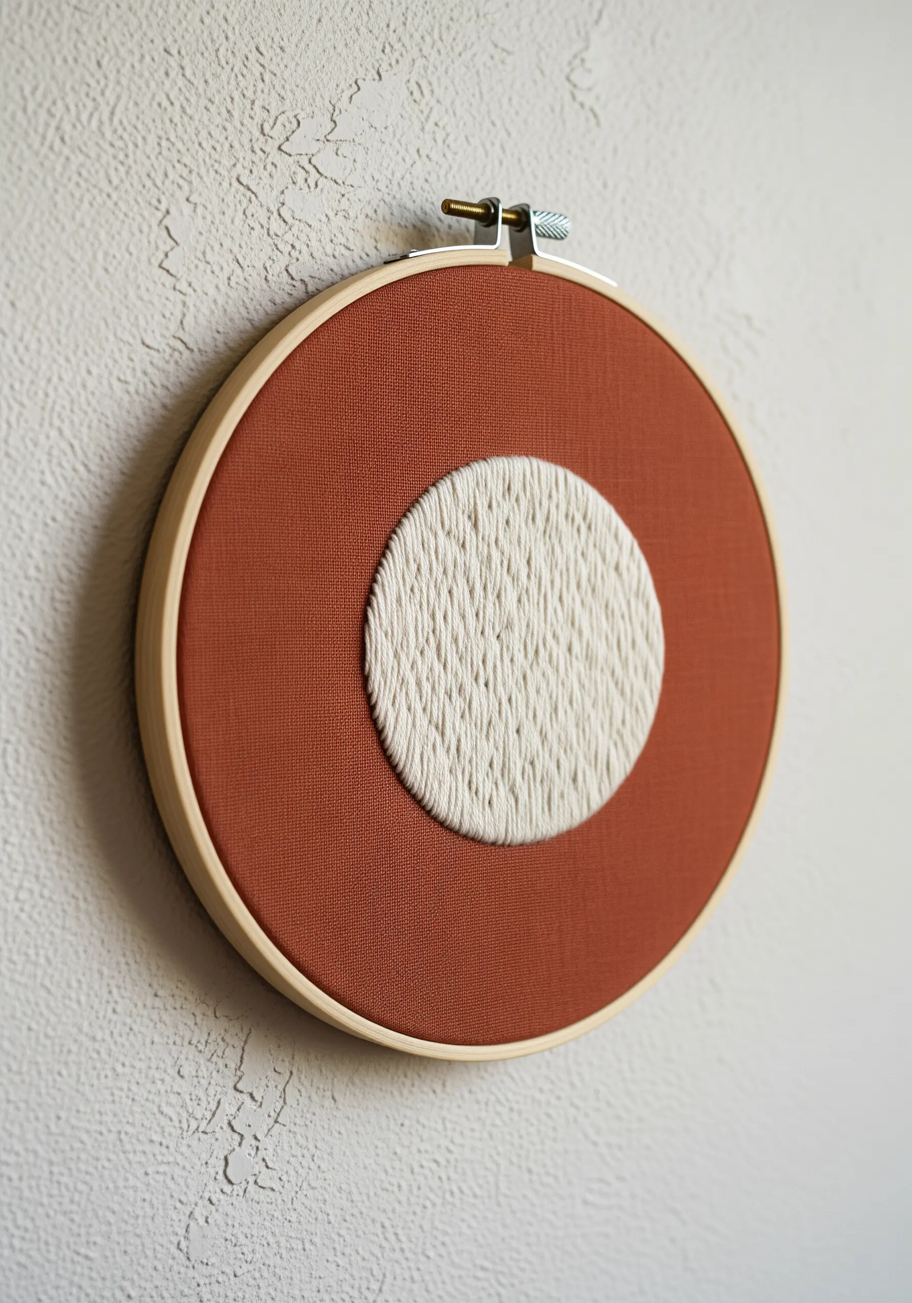 A heavily textured white circle stitched in the center of rust-colored fabric.