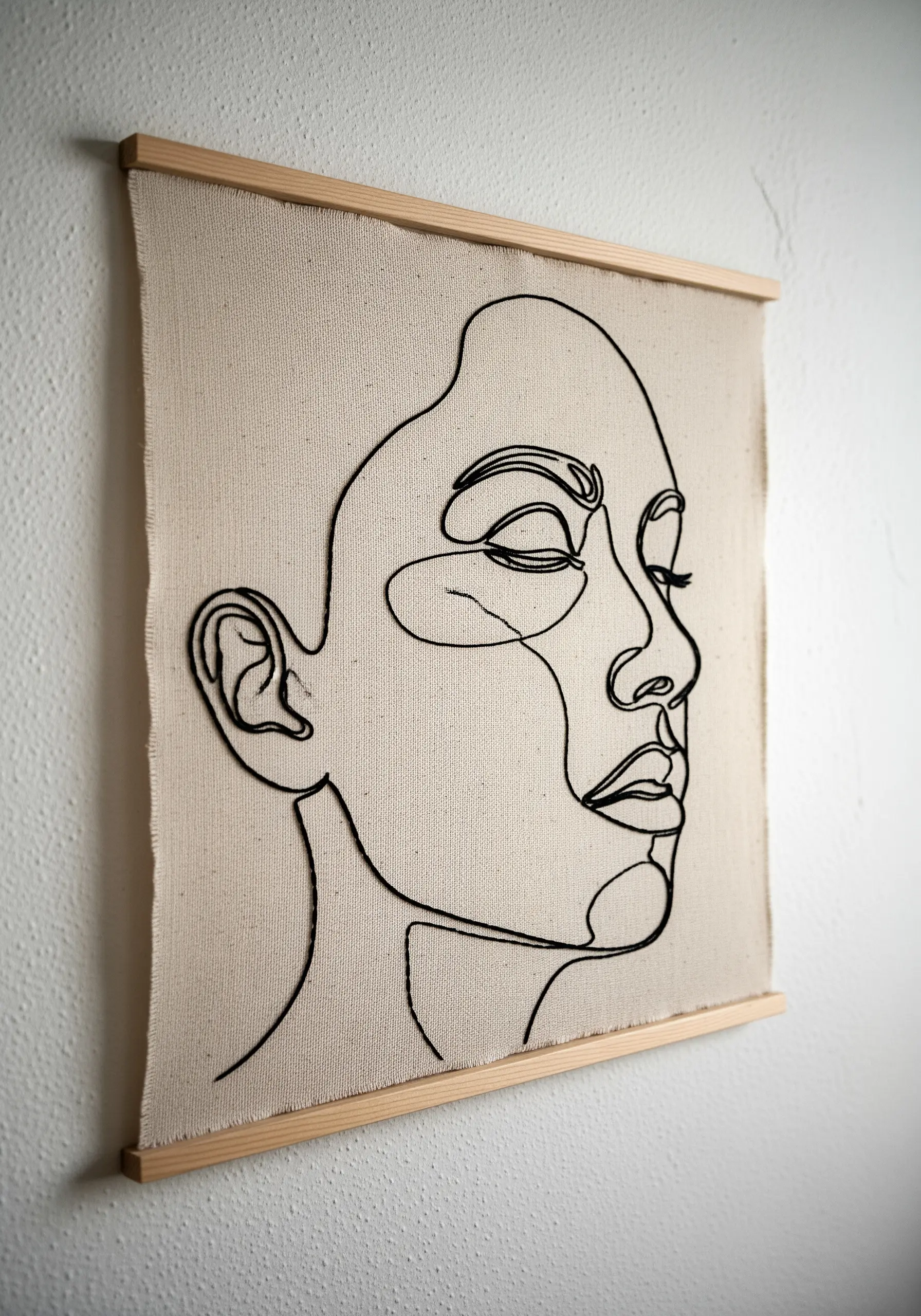 A minimalist portrait created with a single continuous black cord on neutral linen.
