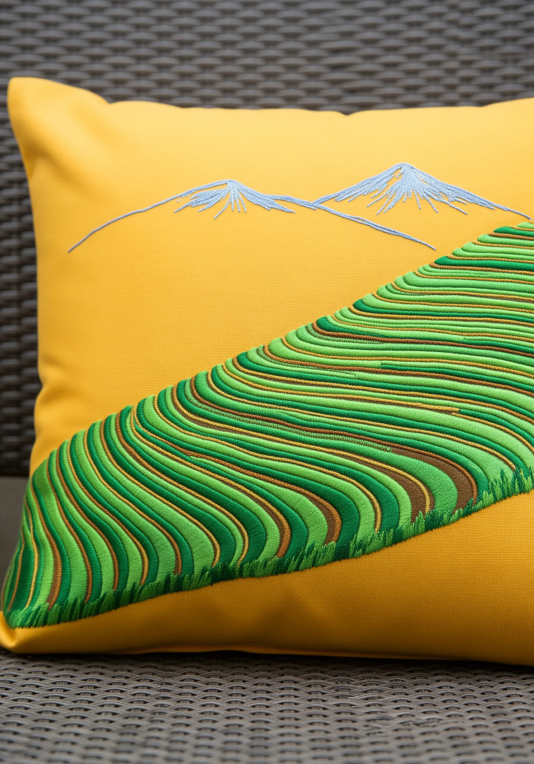 Embroidered green rice terraces with raised outlines on a bright yellow pillow.