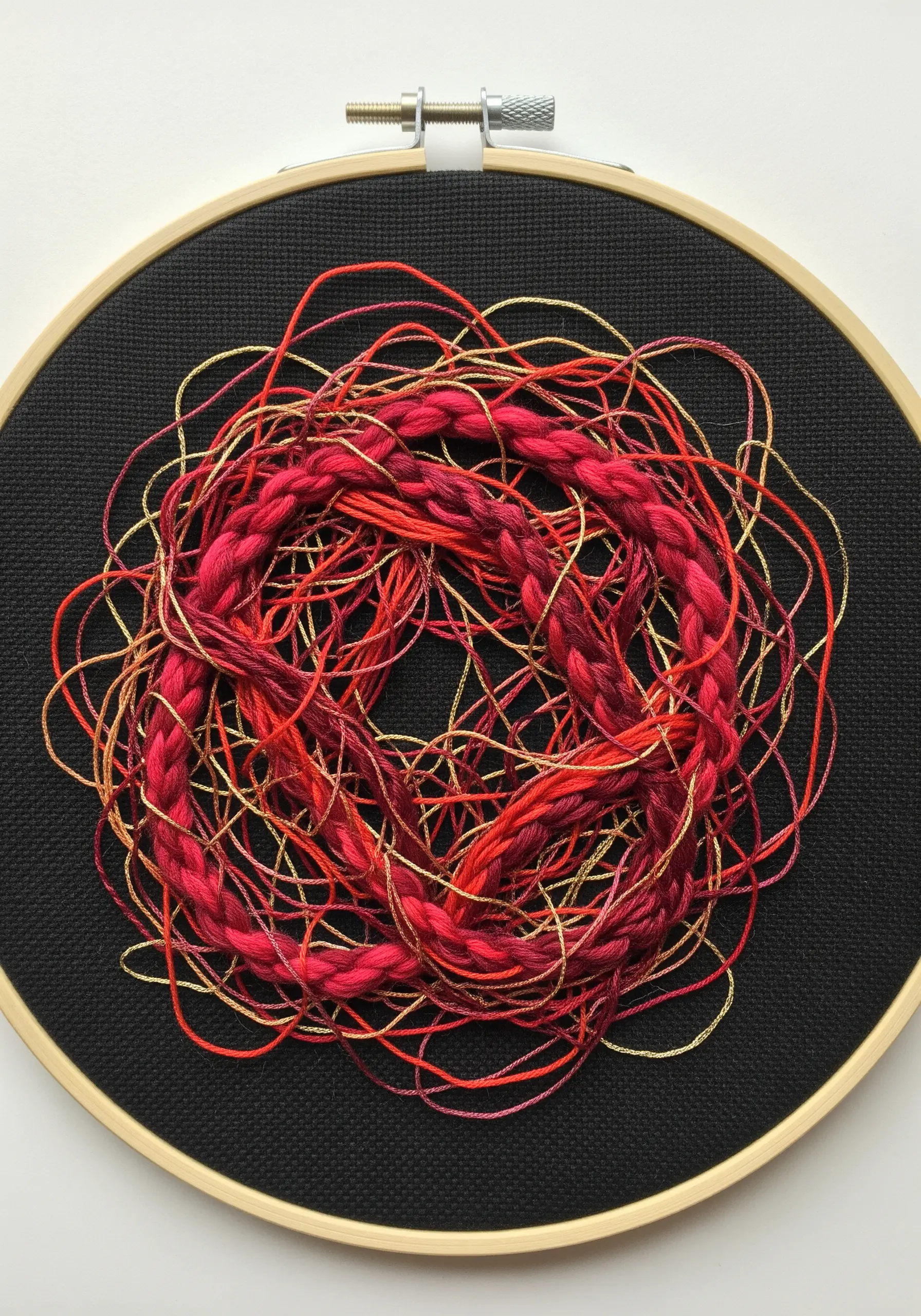 A circular composition of braided and tangled red threads on black fabric.