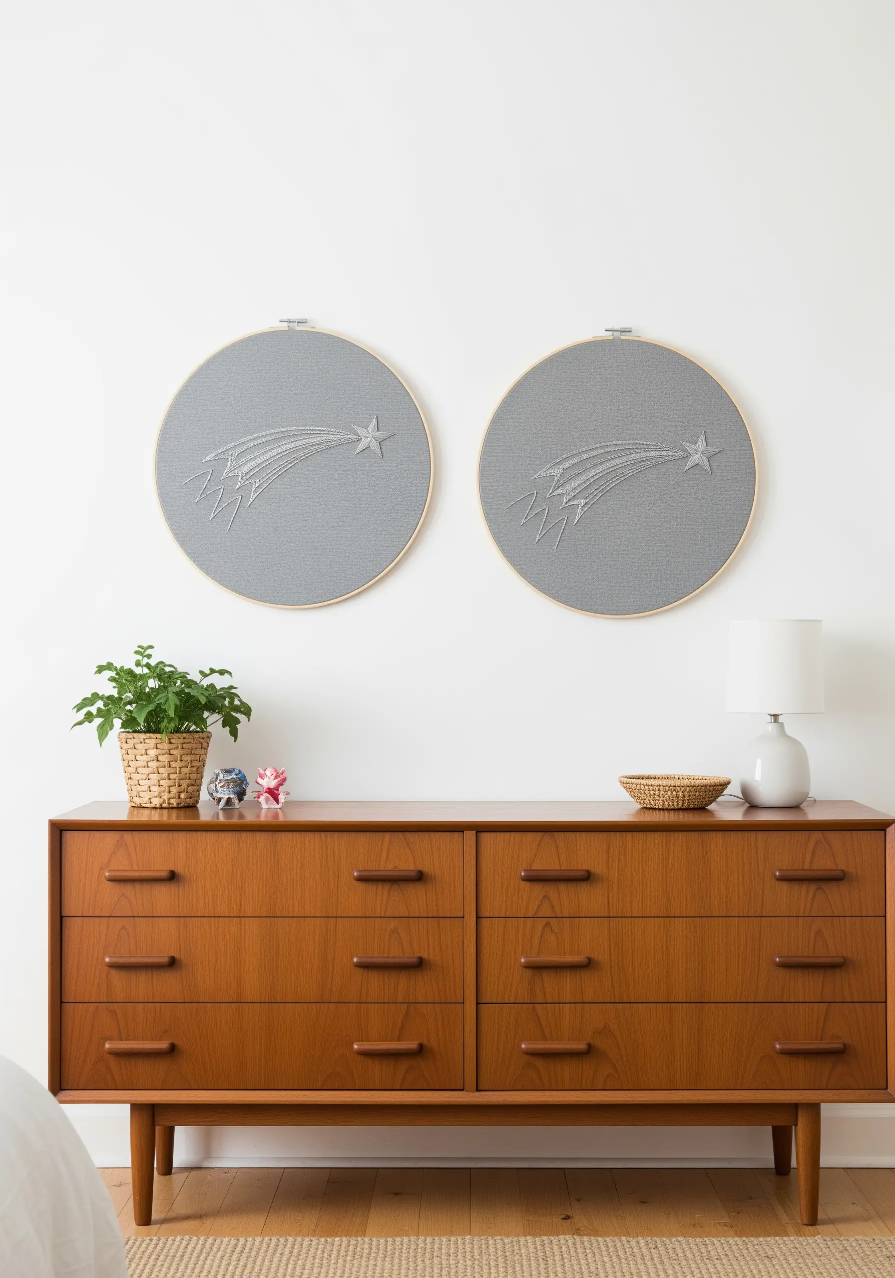 A diptych of two shooting star embroideries on grey fabric above a dresser.