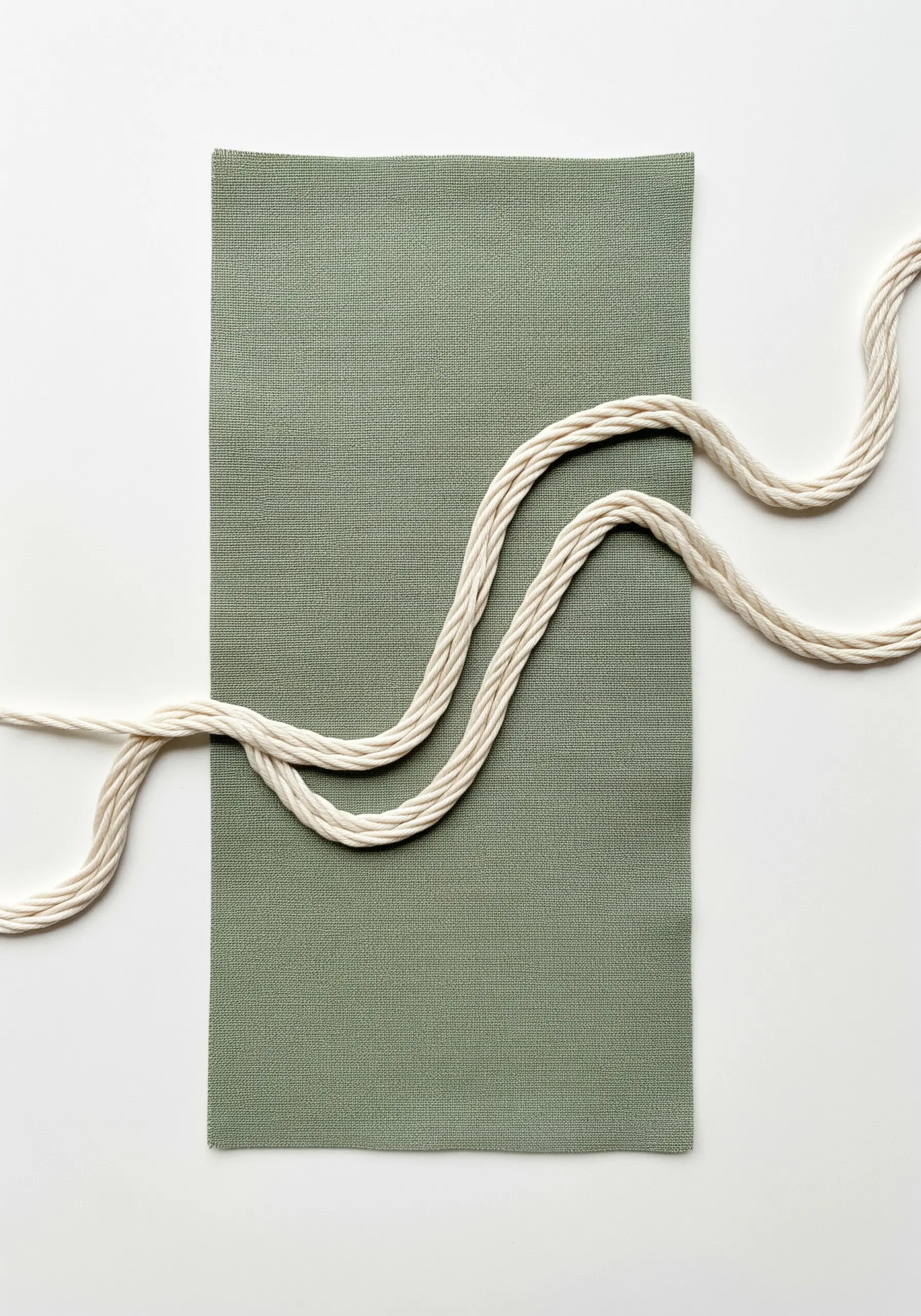 A swatch of green fabric with a thick, winding cream-colored cord couched onto its surface.
