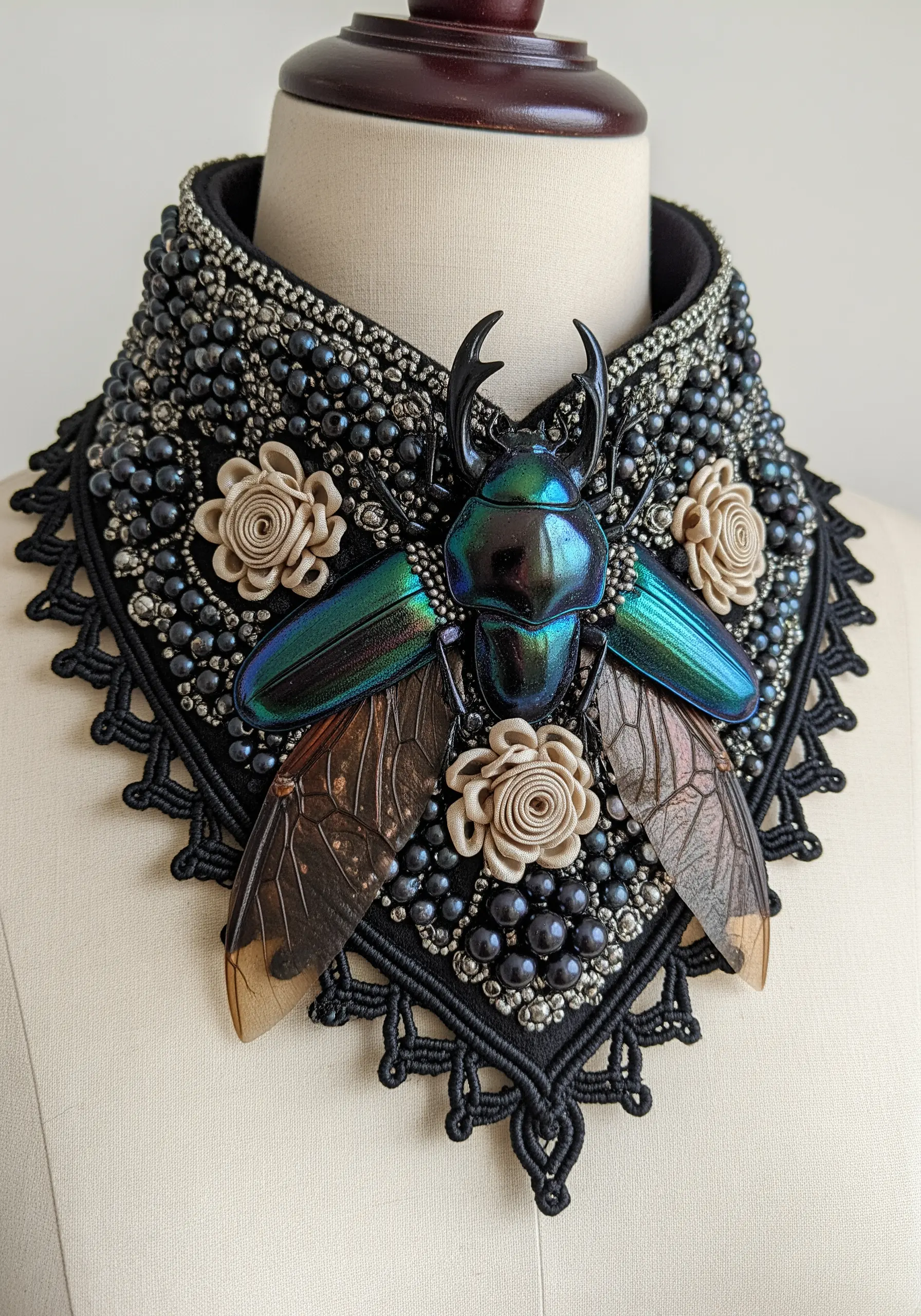 An ornate beaded collar featuring a large iridescent beetle, pearls, and black lace trim.