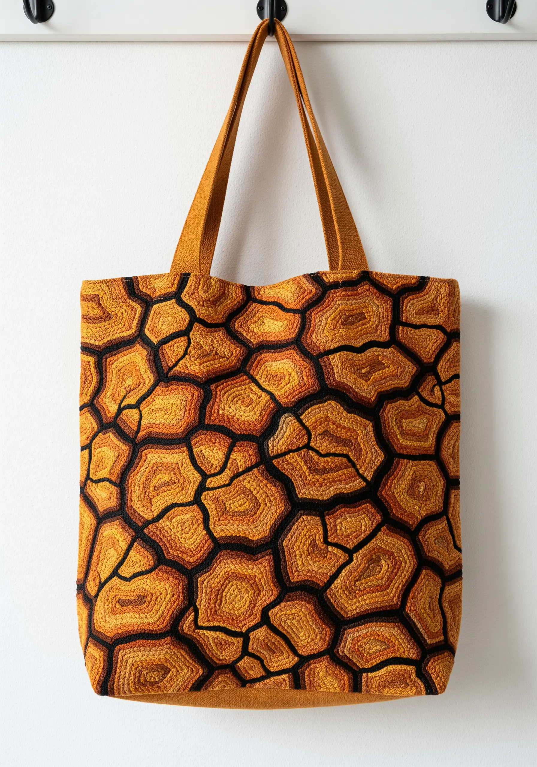 Tote bag fully embroidered with a cracked earth pattern in shades of orange, yellow, and brown.