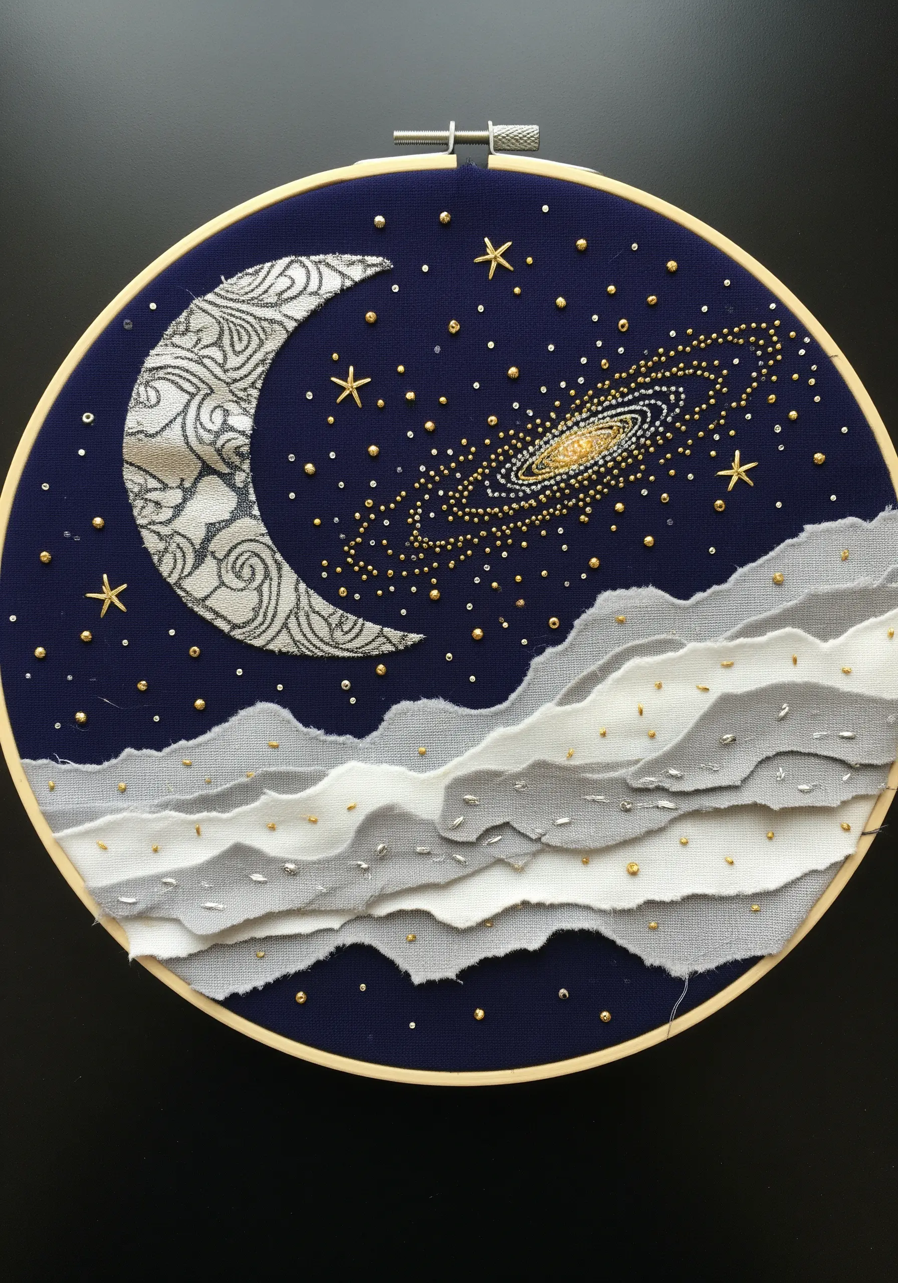 Celestial hoop art with an appliqué moon, layered fabric clouds, and beaded stars.