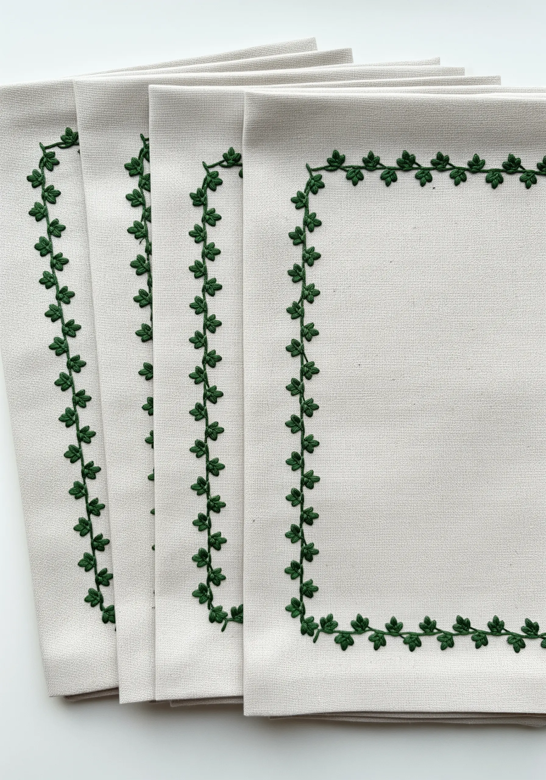 A stack of napkins with a simple, delicate border of tiny green ivy leaves.