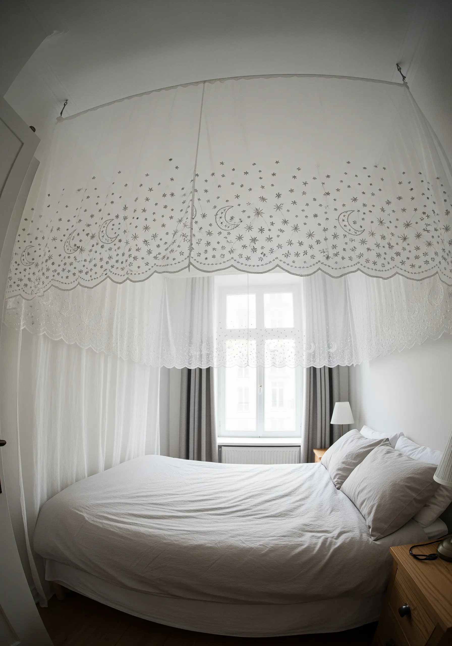 A sheer white bed canopy embroidered with delicate moons and stars.