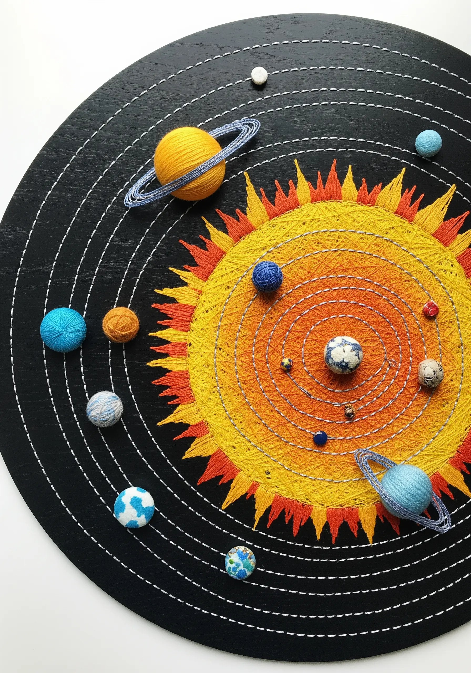 A string art solar system with planets made from colorful wrapped yarn balls on a black board.