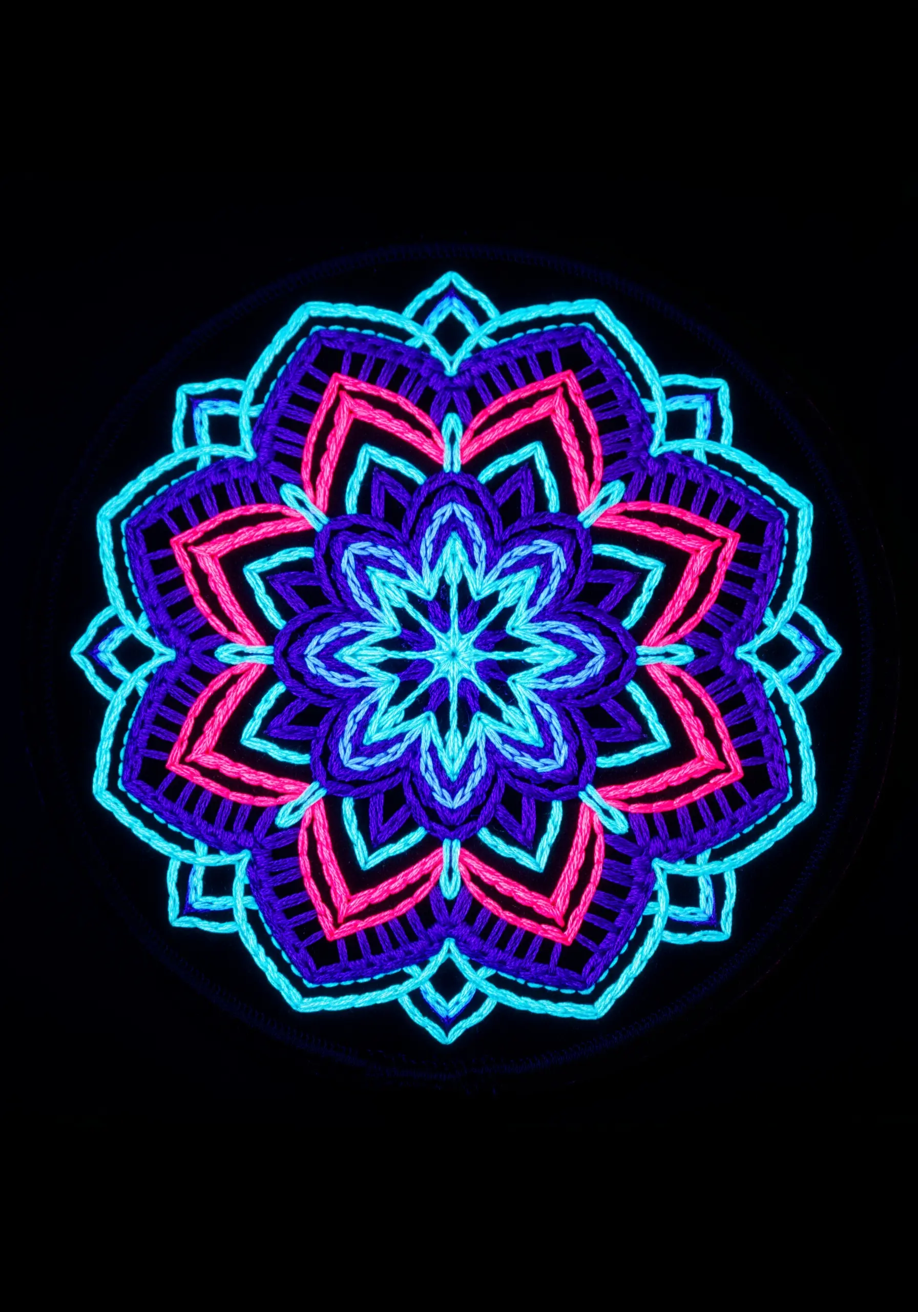 A vibrant, glowing mandala in neon blue, pink, and purple on a black background.