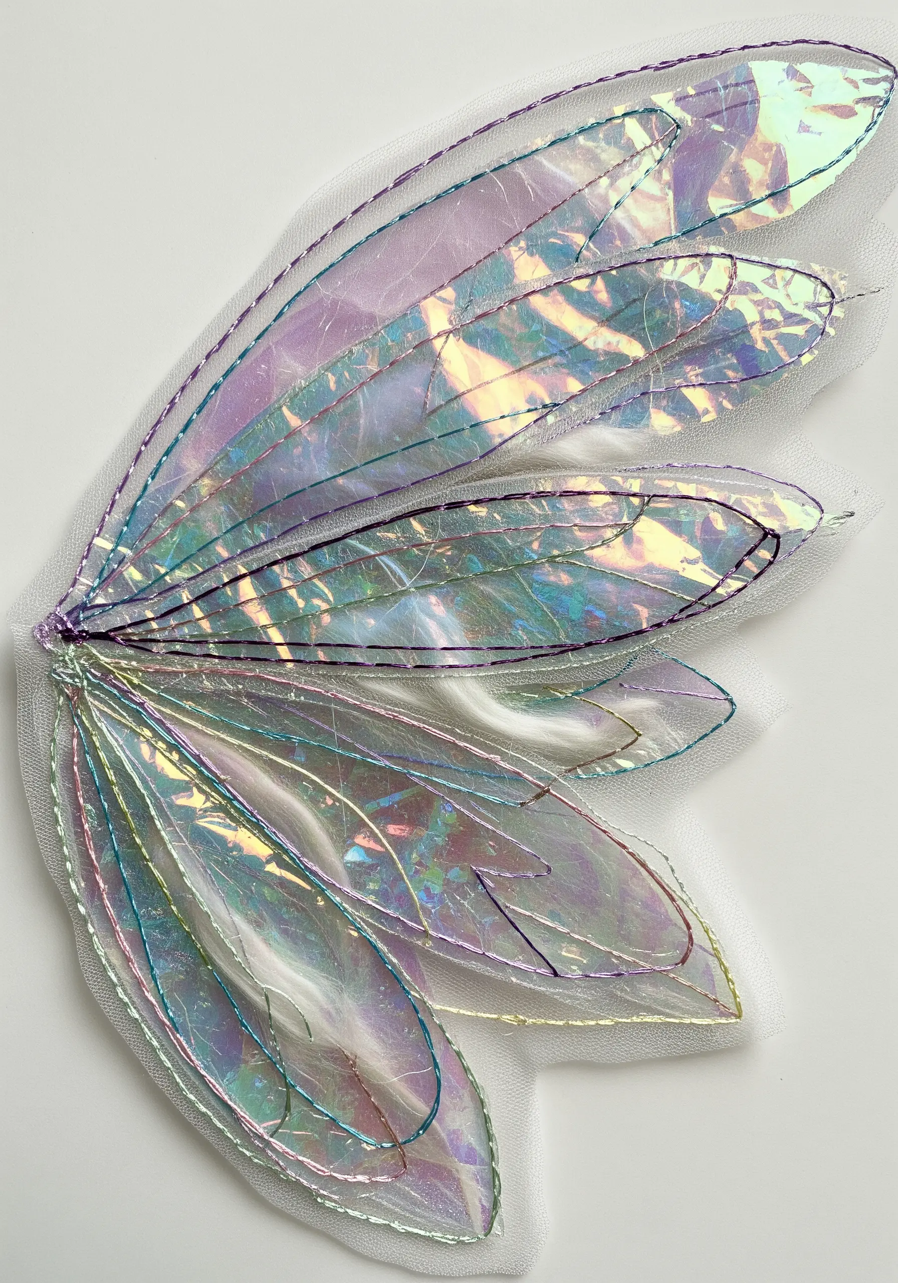 Iridescent fairy wings made from layered cellophane and tulle, with stitched details.