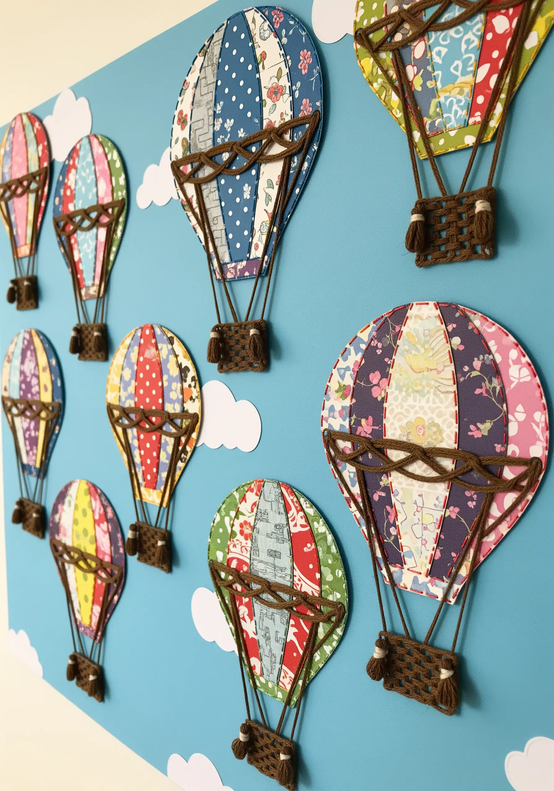 Hot air balloons made from patterned paper collage with woven yarn baskets and details.