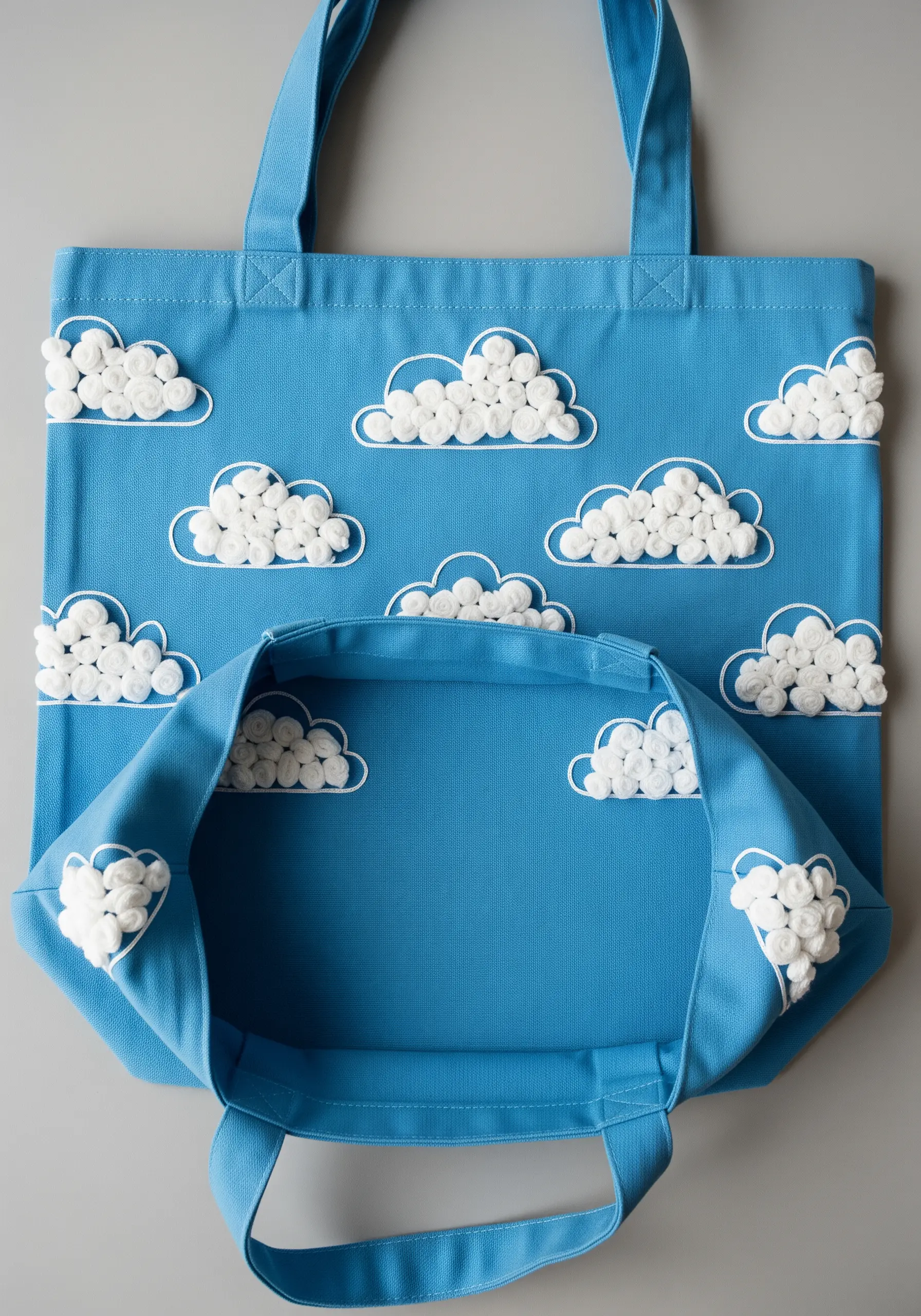 A pattern of fluffy 3D clouds made from woven wheel stitches on a blue tote.