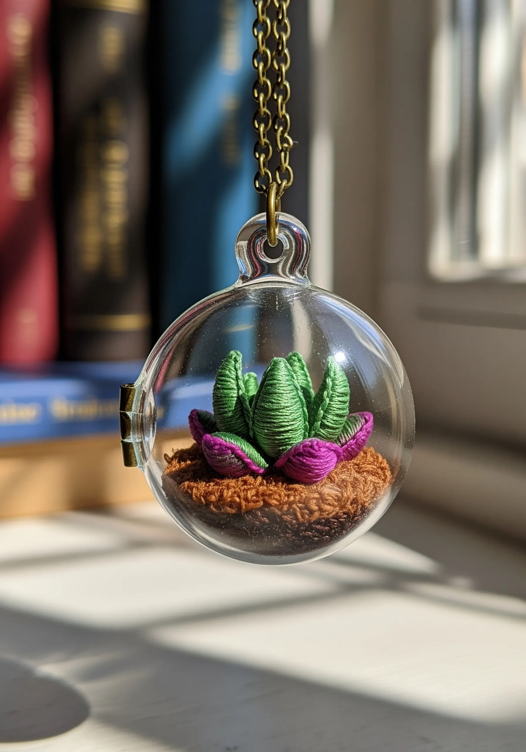 3D embroidered succulent with padded satin stitch inside a miniature glass locket.