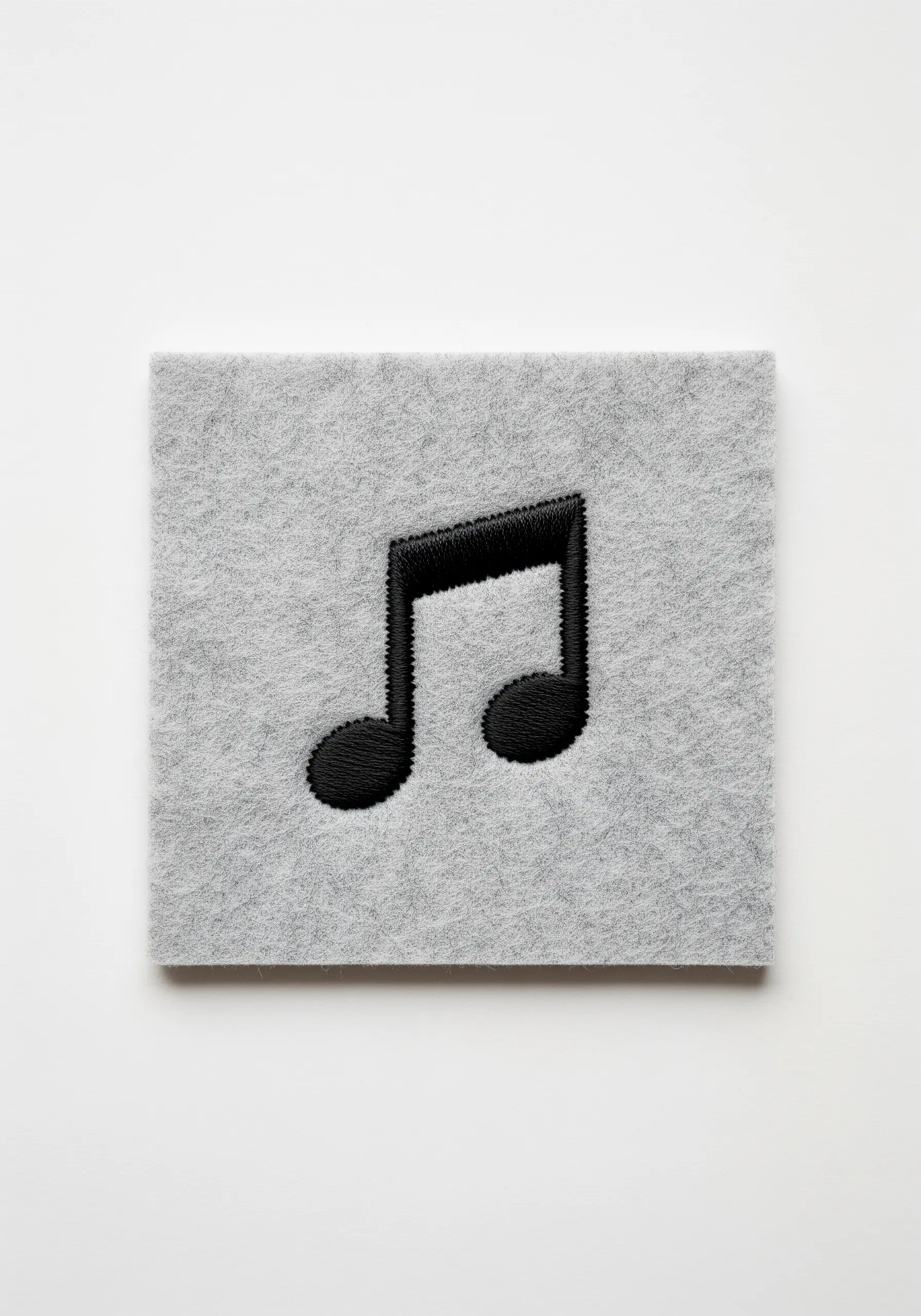 A black musical note with a raised, polished effect from padded satin stitch.