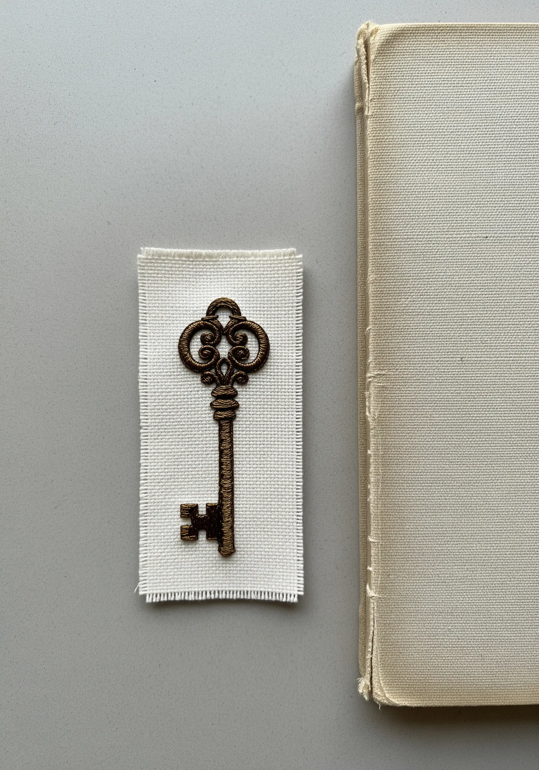 A vintage key embroidered with padded satin stitch to create a raised, 3D effect.