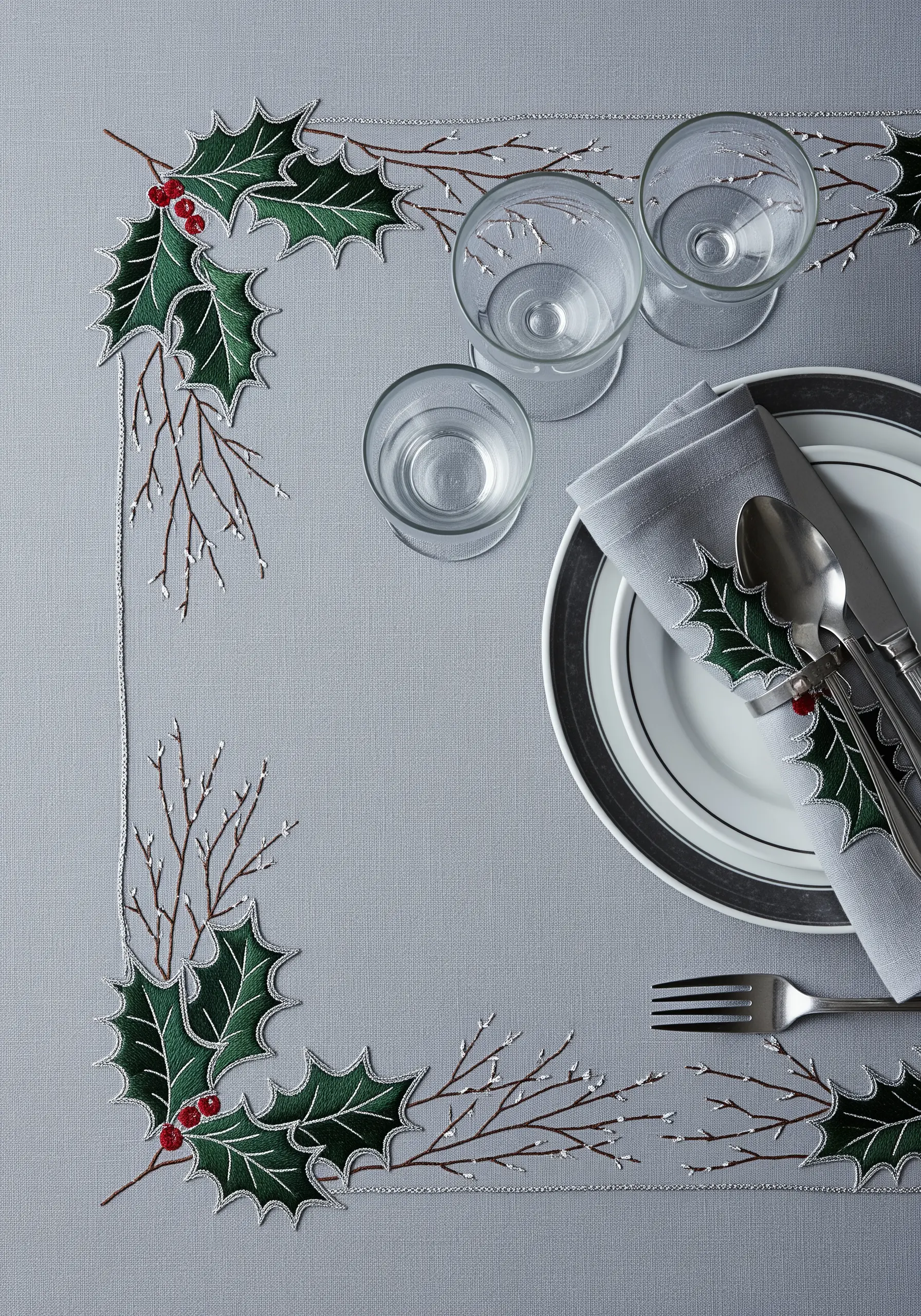 A festive border of embroidered holly leaves, red berries, and delicate bare branches.