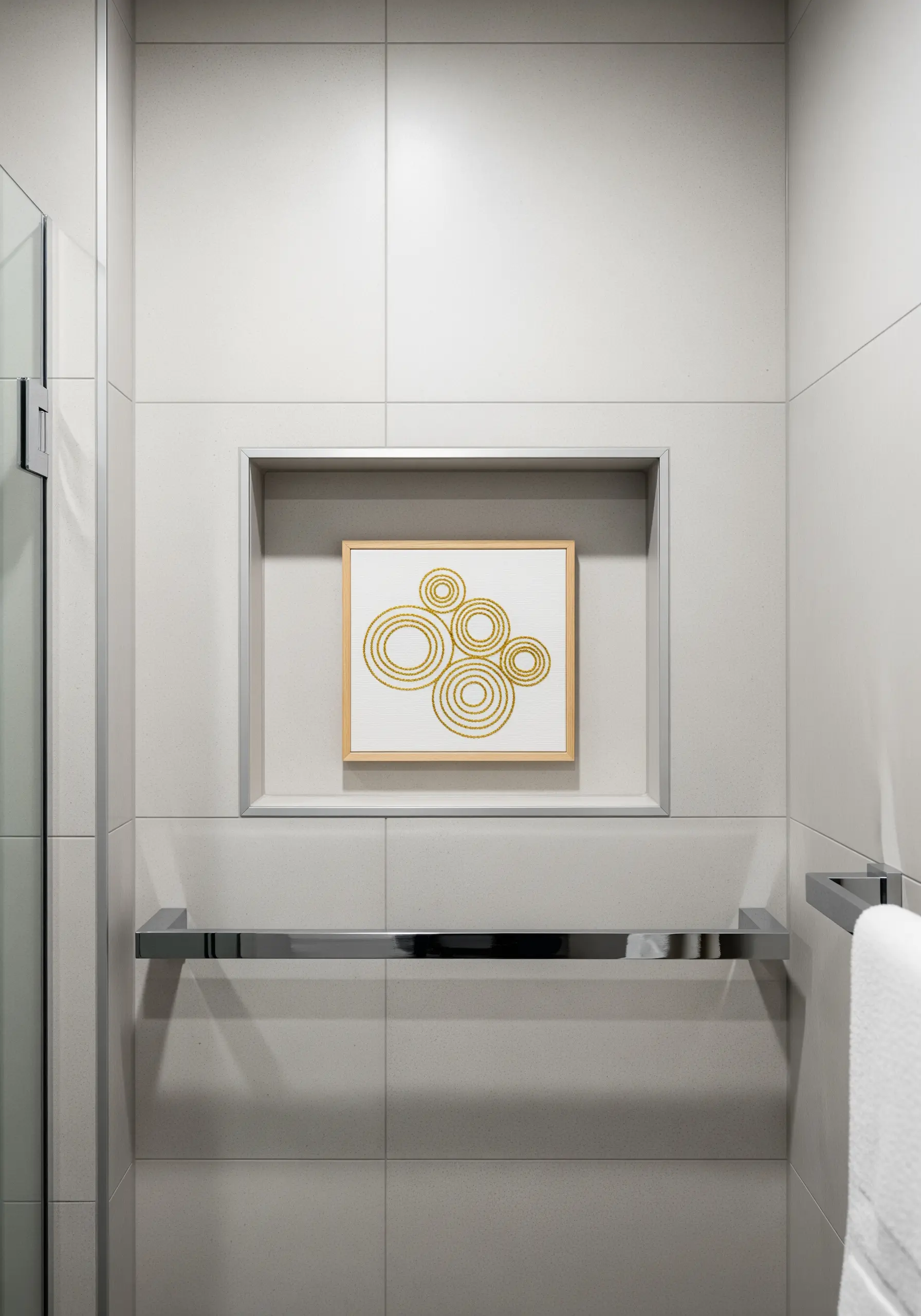 Framed embroidery of overlapping concentric circles in gold thread, placed in a bathroom niche.