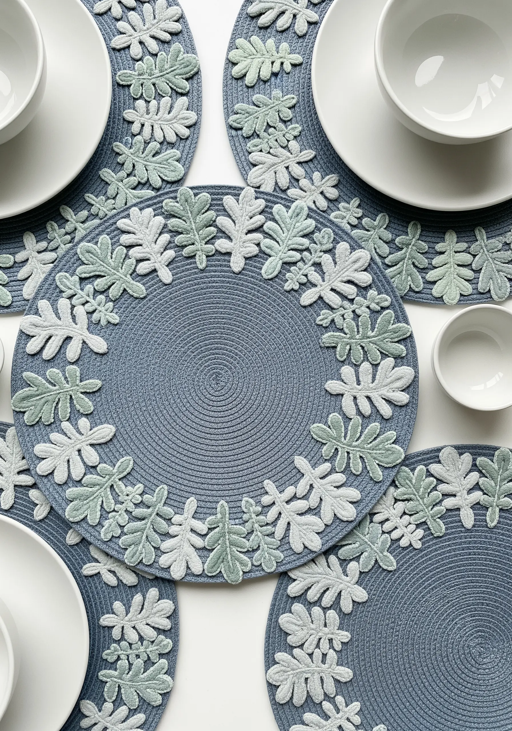 Round placemats with a border of appliqué-style leaves in mint green and white.