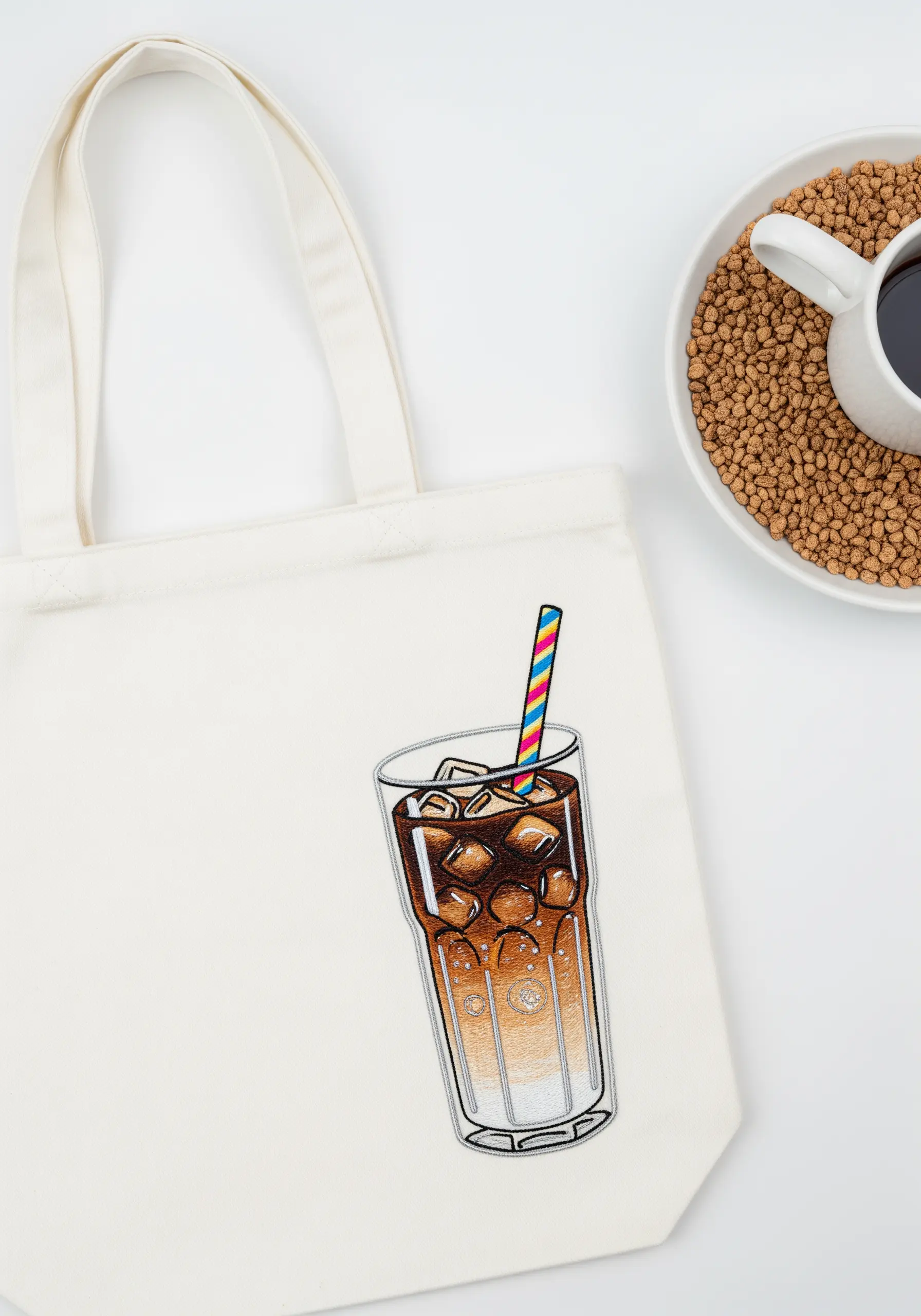 Embroidery of a tall glass of iced coffee showing a gradient from dark coffee to creamy milk.