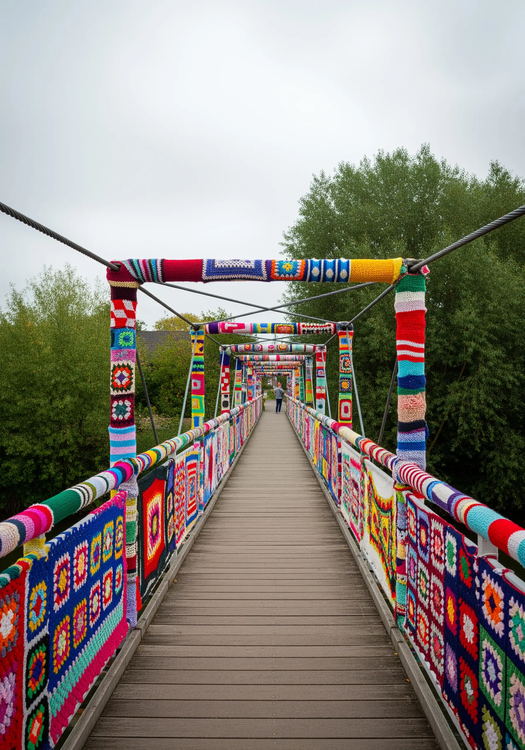 A long footbridge completely covered in colorful, patterned granny squares and crocheted panels.