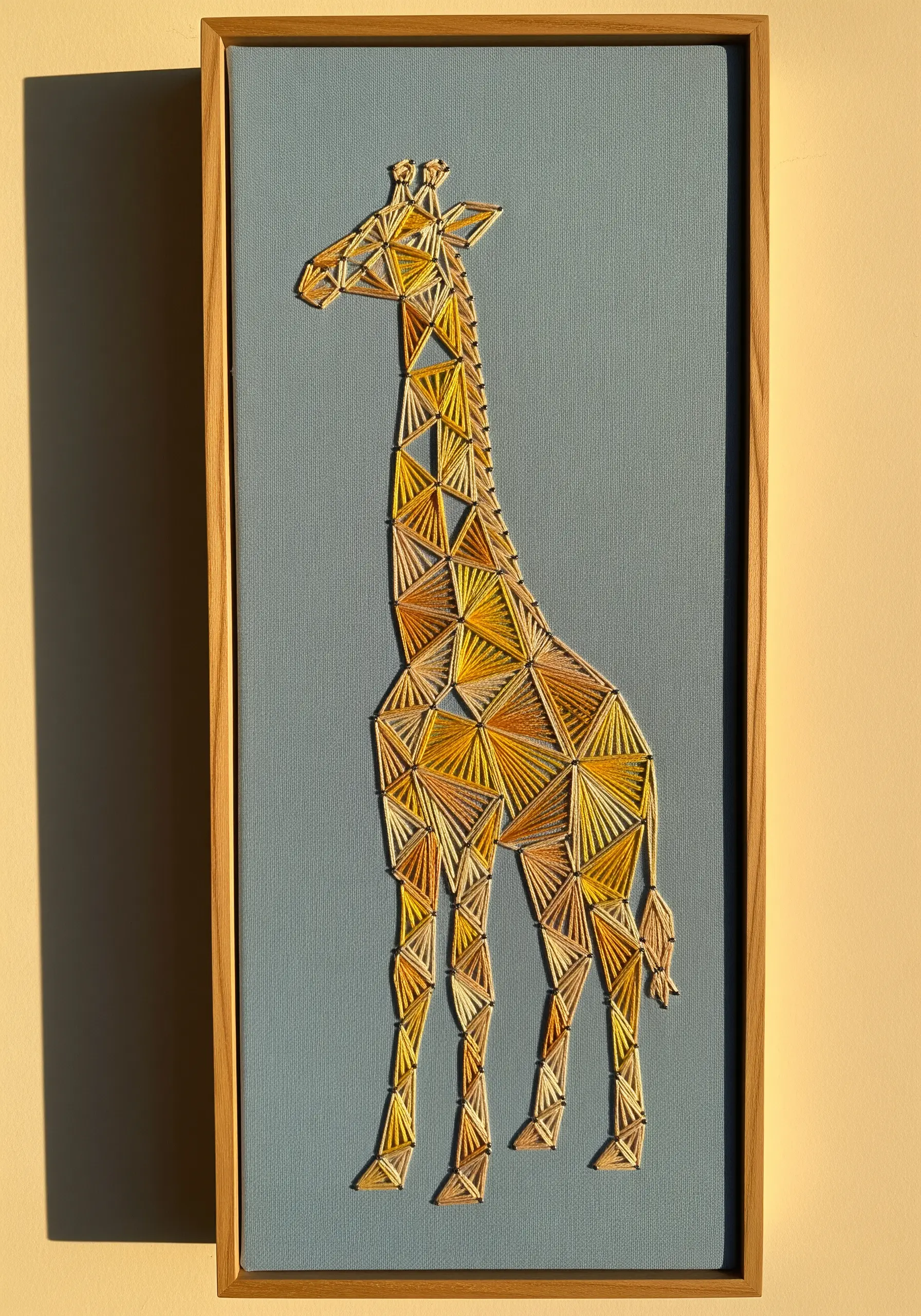 Geometric giraffe embroidery with yellow and gold patchwork-style stitching on blue fabric.