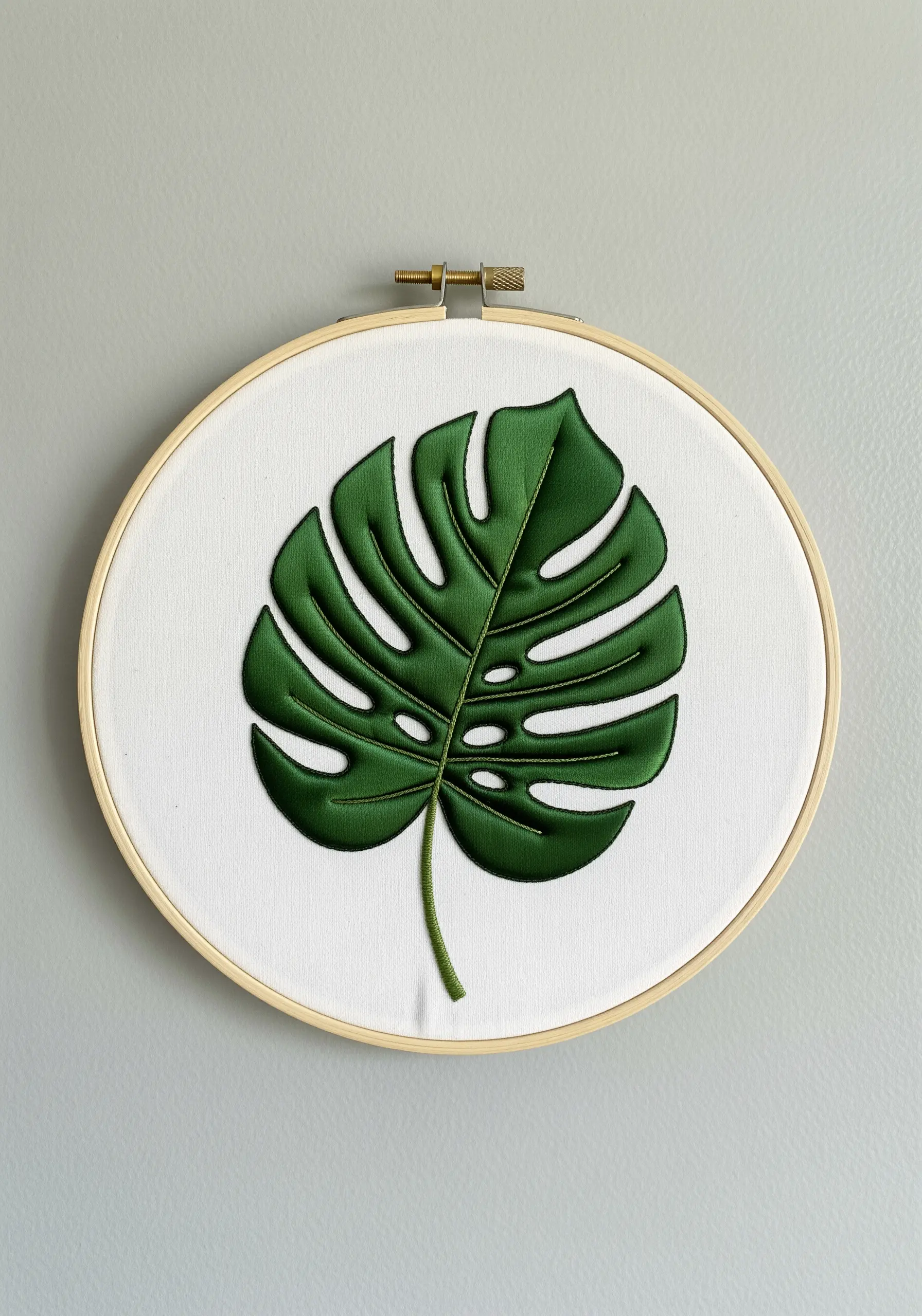 A perfectly smooth, dark green embroidered Monstera leaf with a padded satin stitch finish.