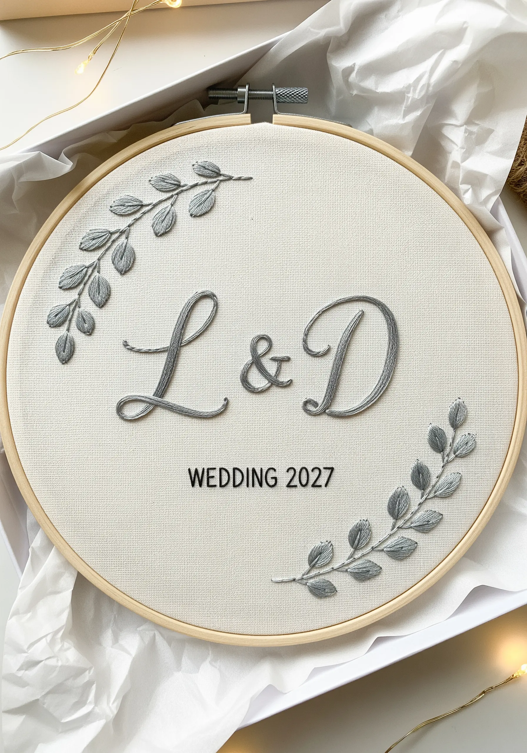 A wedding embroidery hoop with raised satin stitch initials 'L & D' in elegant gray thread.