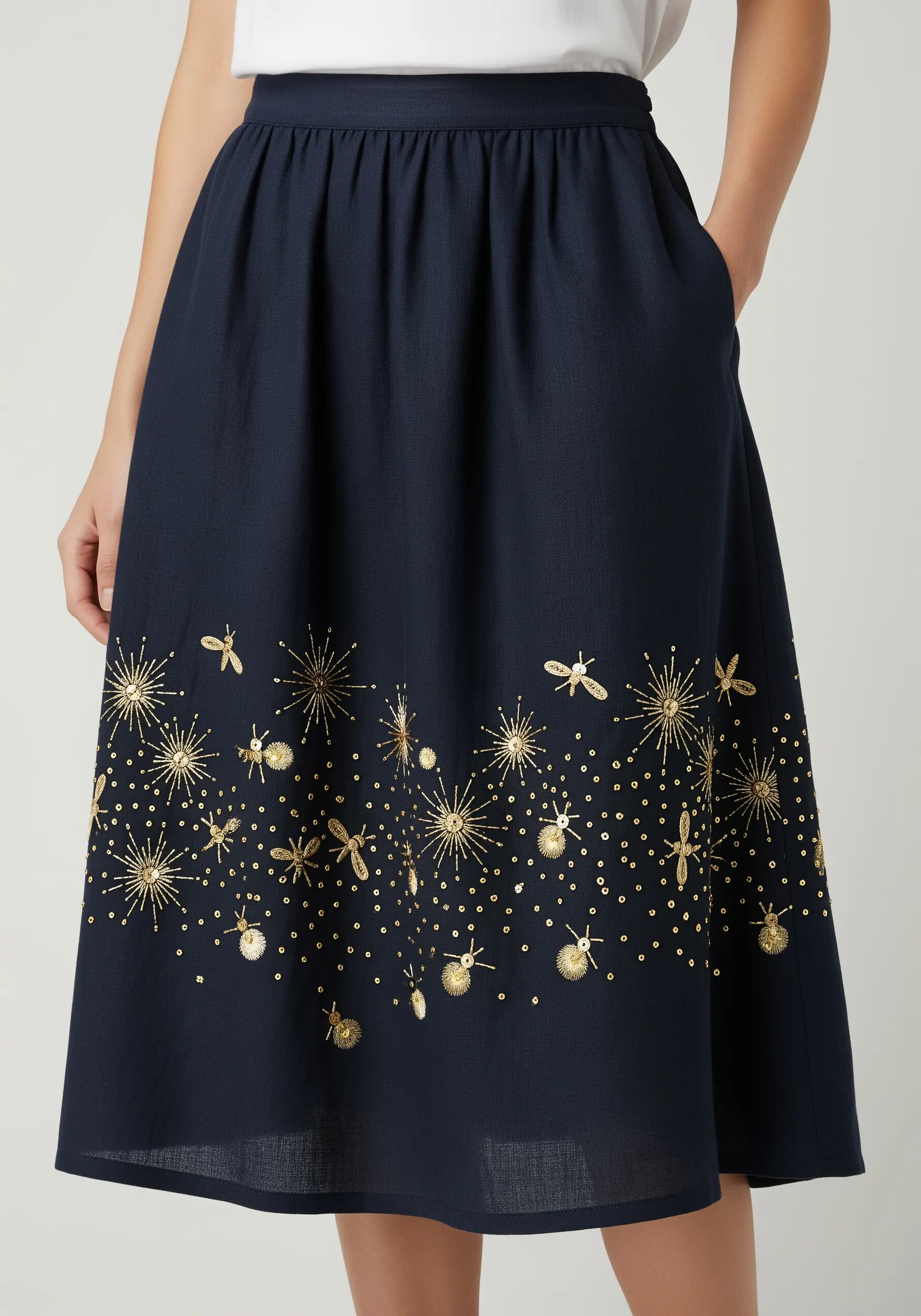 Gold metallic thread and sequin embroidery of starbursts on a navy skirt.