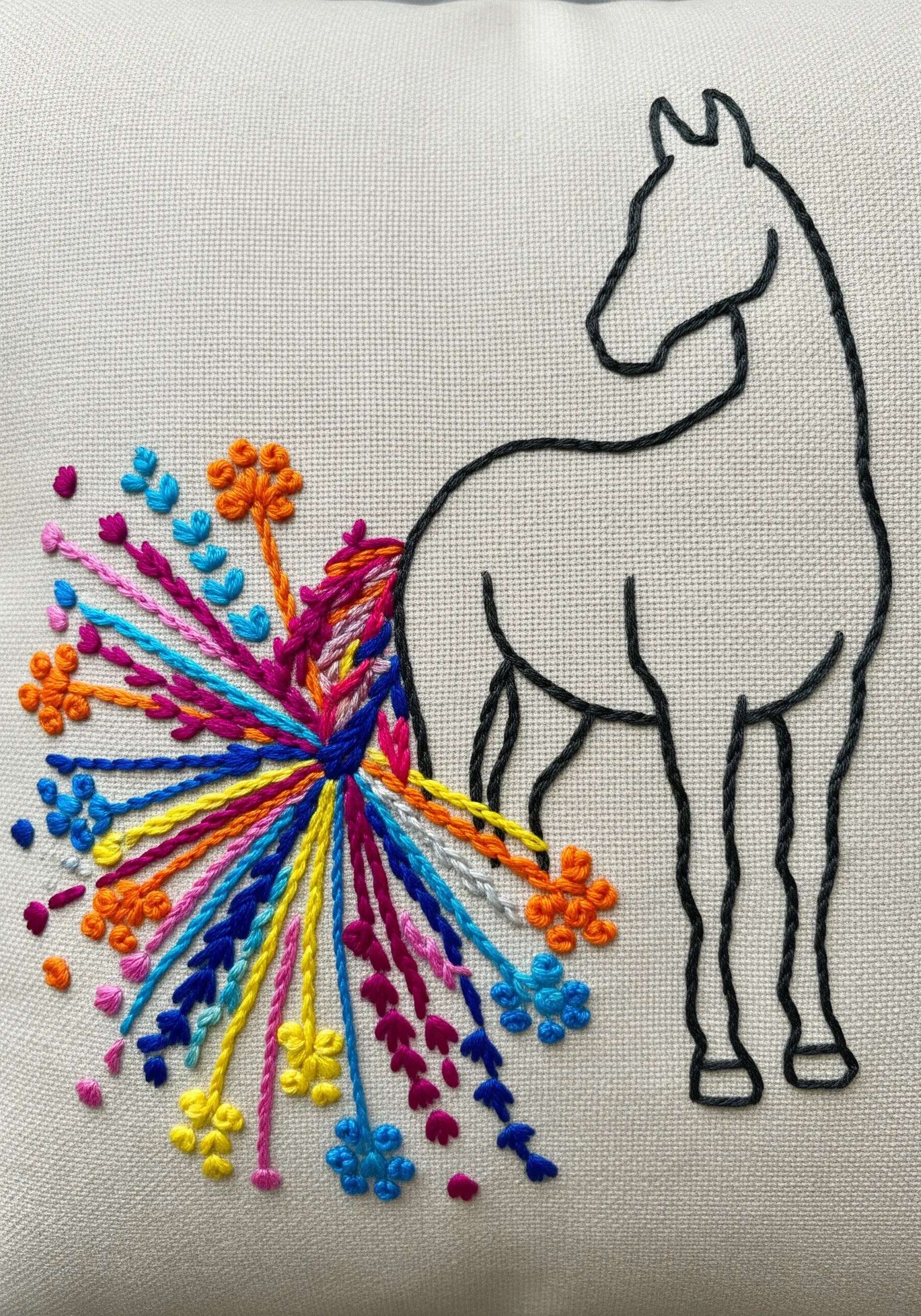 Minimalist horse outline with an abstract, colorful explosion of stitches for a tail.