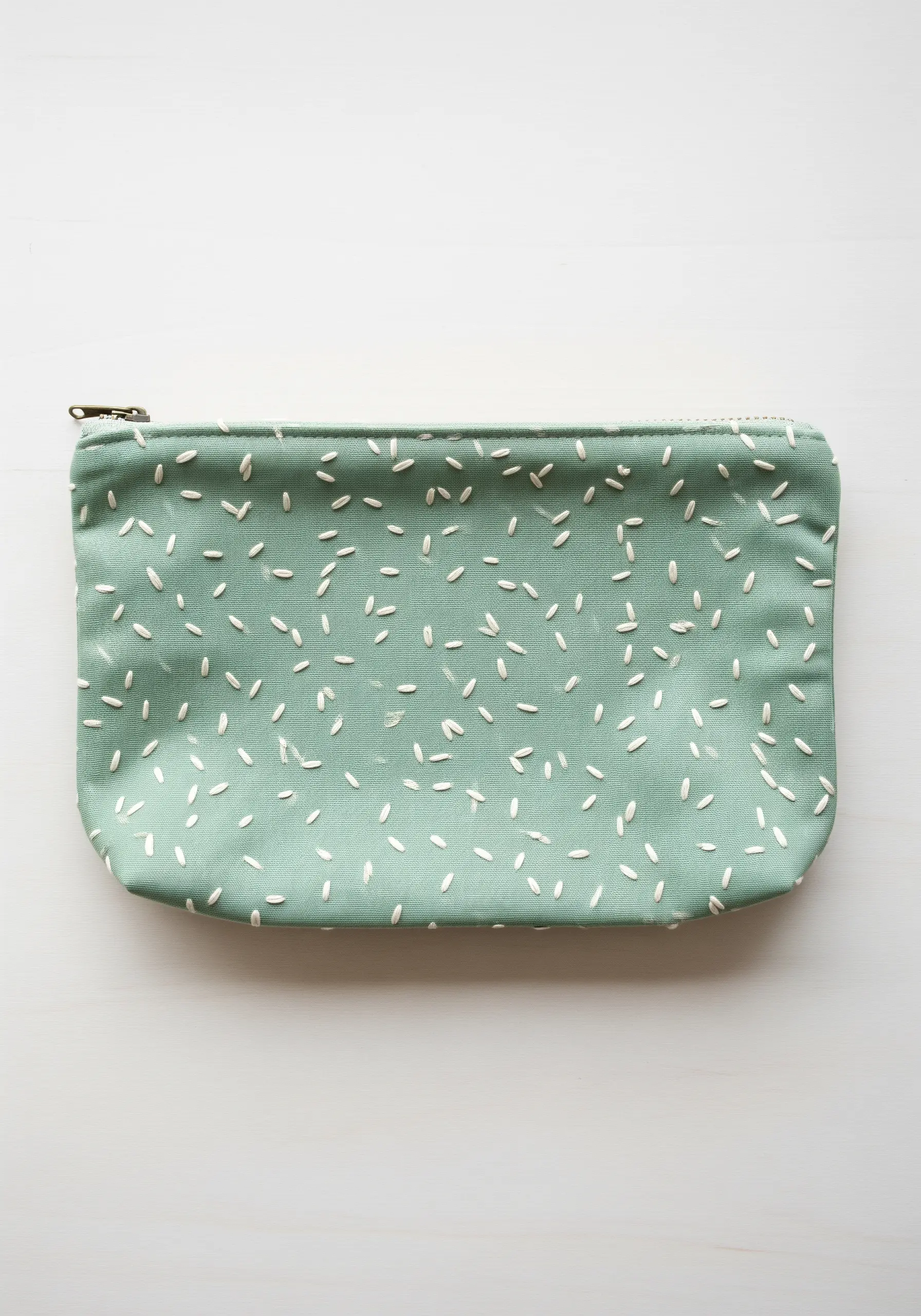 A soft green pouch decorated with an all-over pattern of tiny white seed stitches.